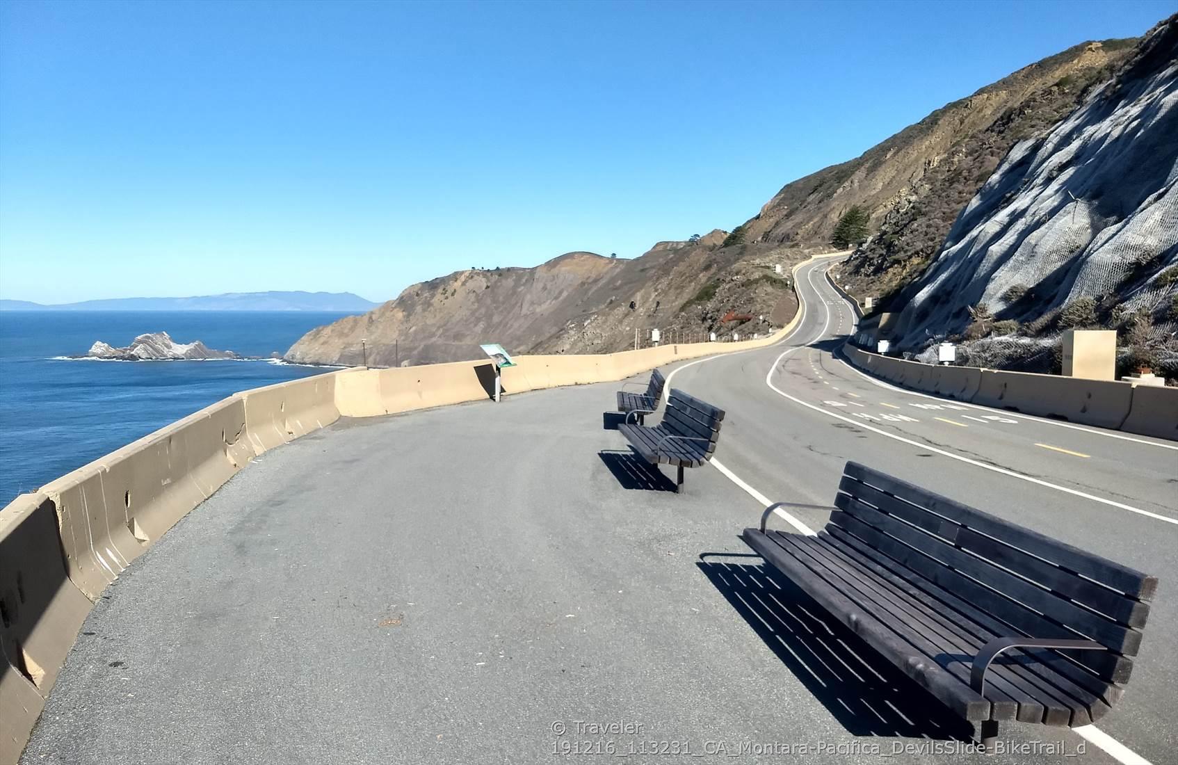 Empty coastal road with benches overlooking the ocean and distant sea stacks.