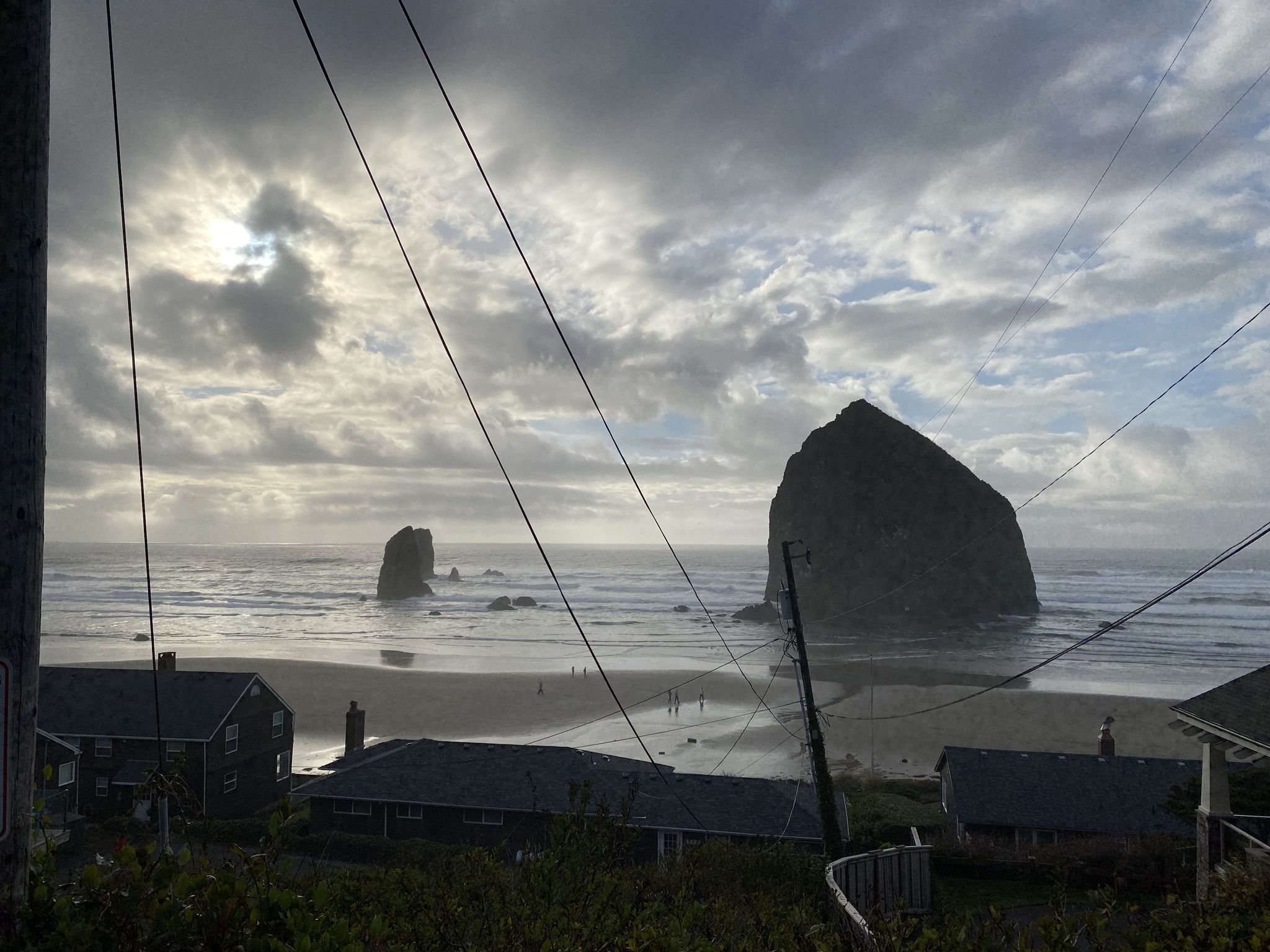 Dramatic cloudy sky over a large sea stack, beach, and coastal houses. - Oregon Coast Trail: Cannon Beach Loop