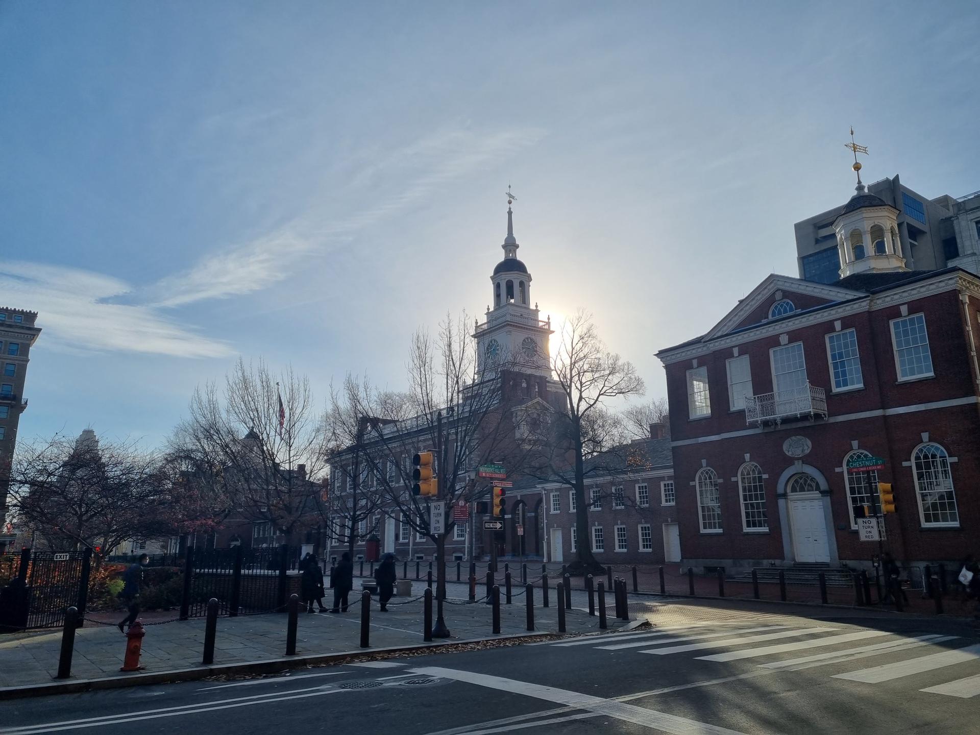 Historic brick buildings with a clock tower under bright sun and clear sky.