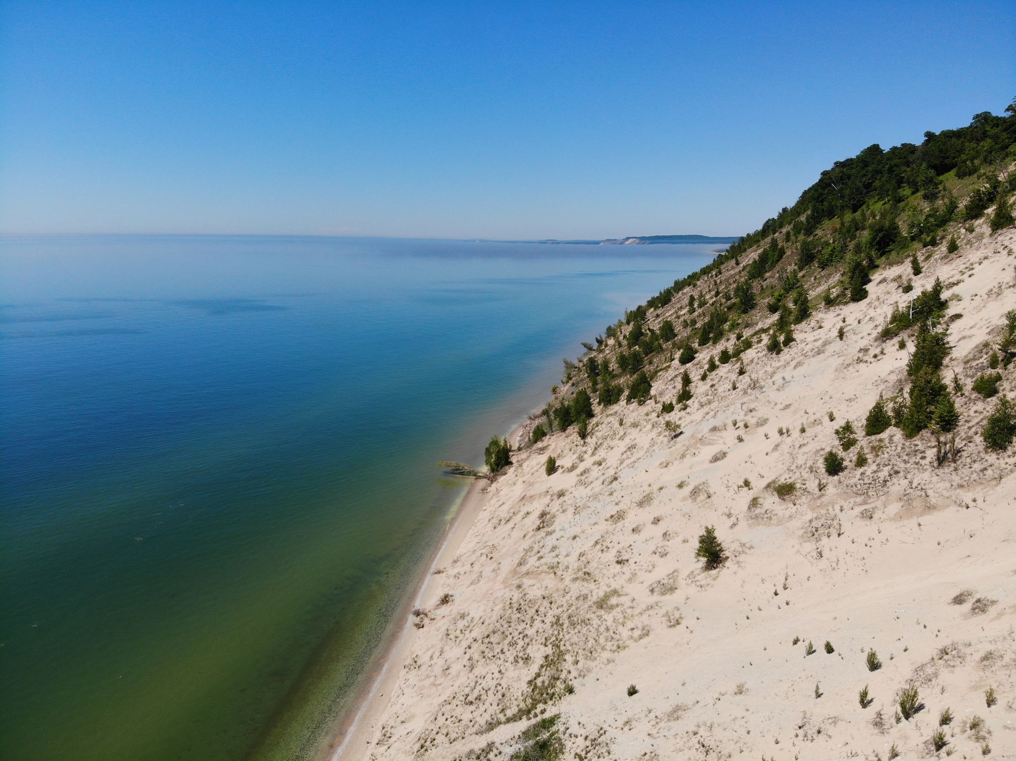 Expansive sandy dune slopes down to clear blue water under a bright sky. - Arcadia - Arcadia Dunes Loop