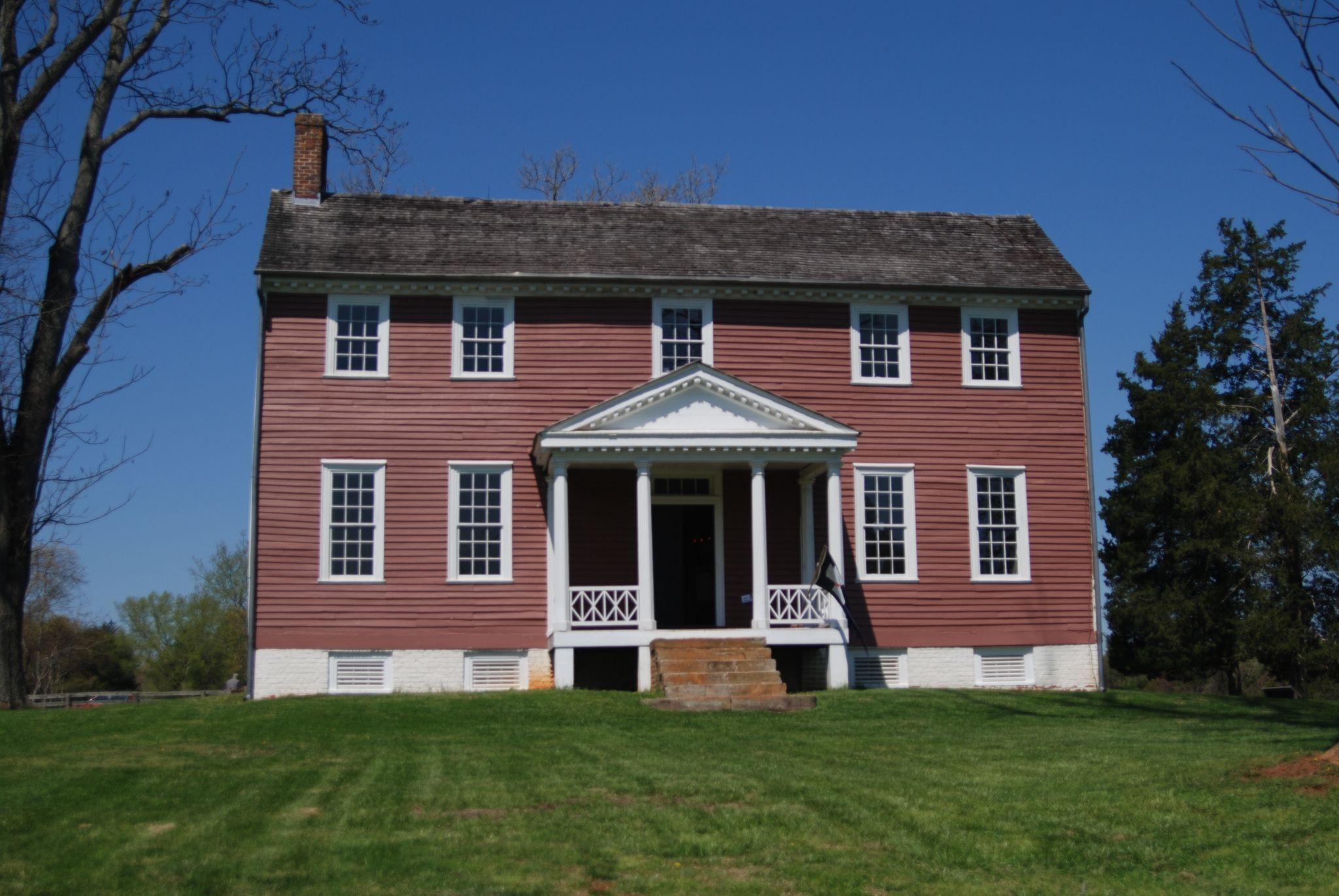 Red historic house with white trim on a green lawn under clear sky. - Spotsylvania Military Park – Lake Anna loop from Spotsylvania Courthouse