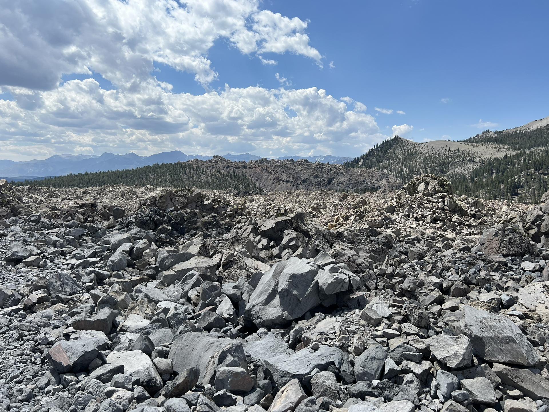 Expansive view of a rocky, barren landscape with distant mountains and a cloudy sky.