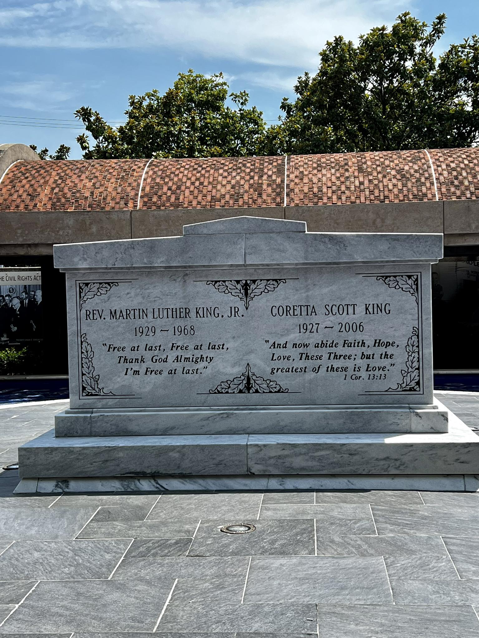 A large white marble tomb under a bright blue sky with trees.