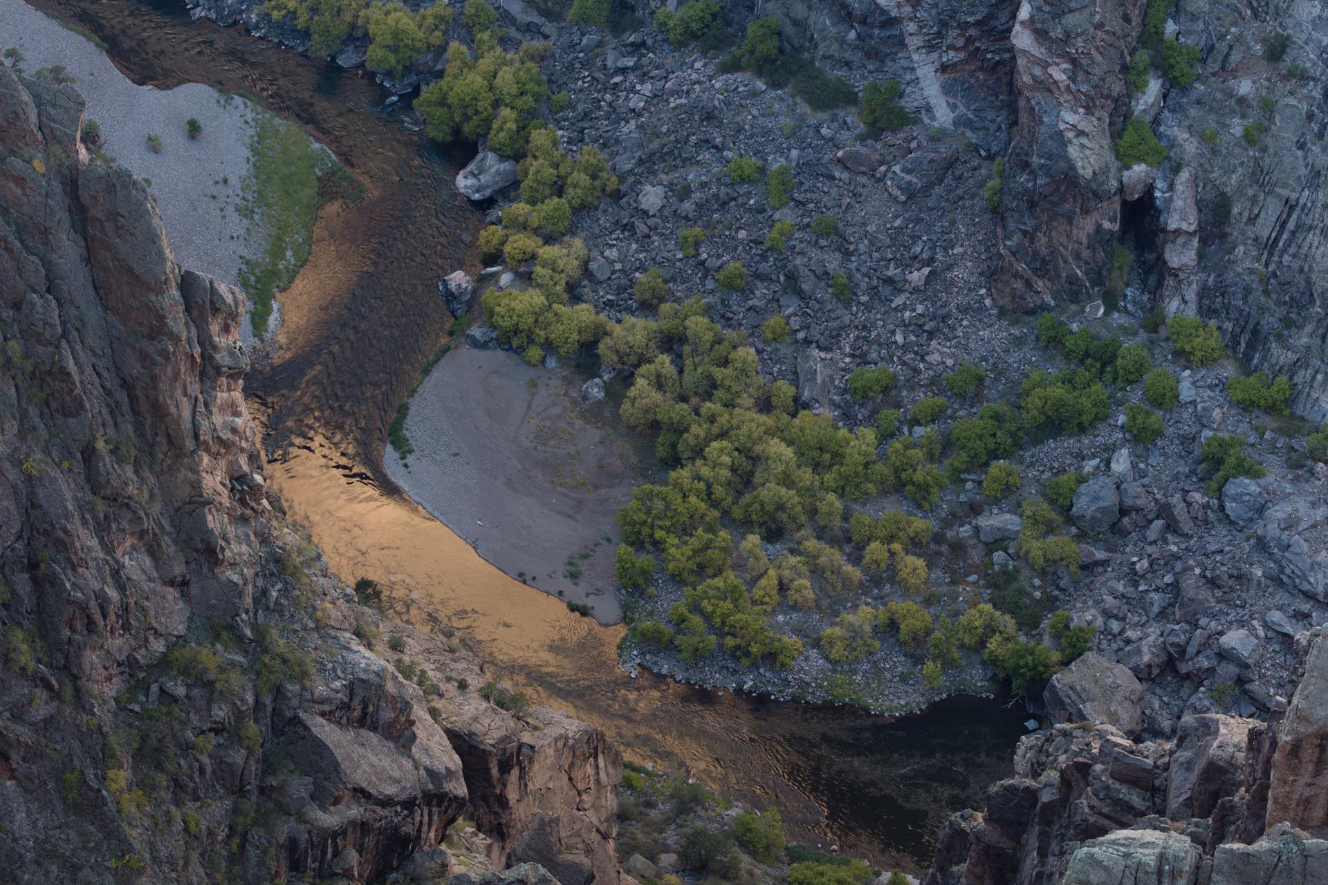 Aerial view of a river winding through a deep, rocky canyon with trees.