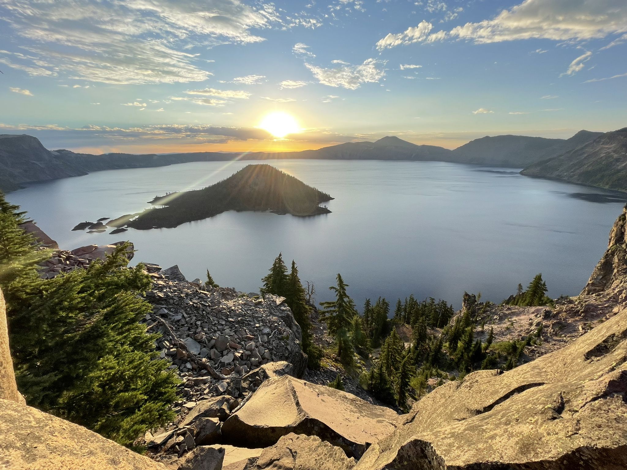 Sunset over a large lake with a central island, rocky foreground. - Rim Drive loop around Crater Lake