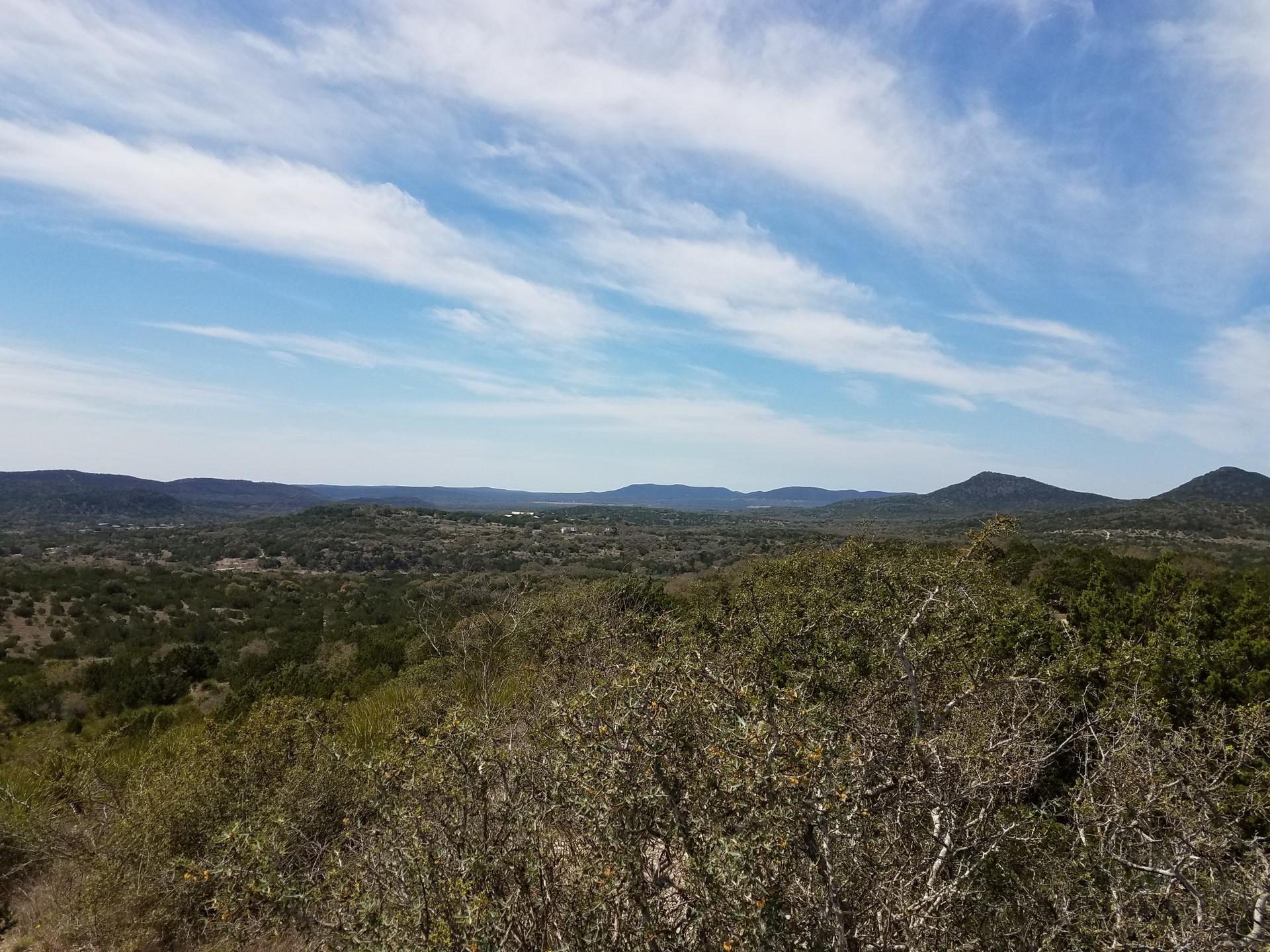 Expansive view of green rolling hills under a bright blue sky.