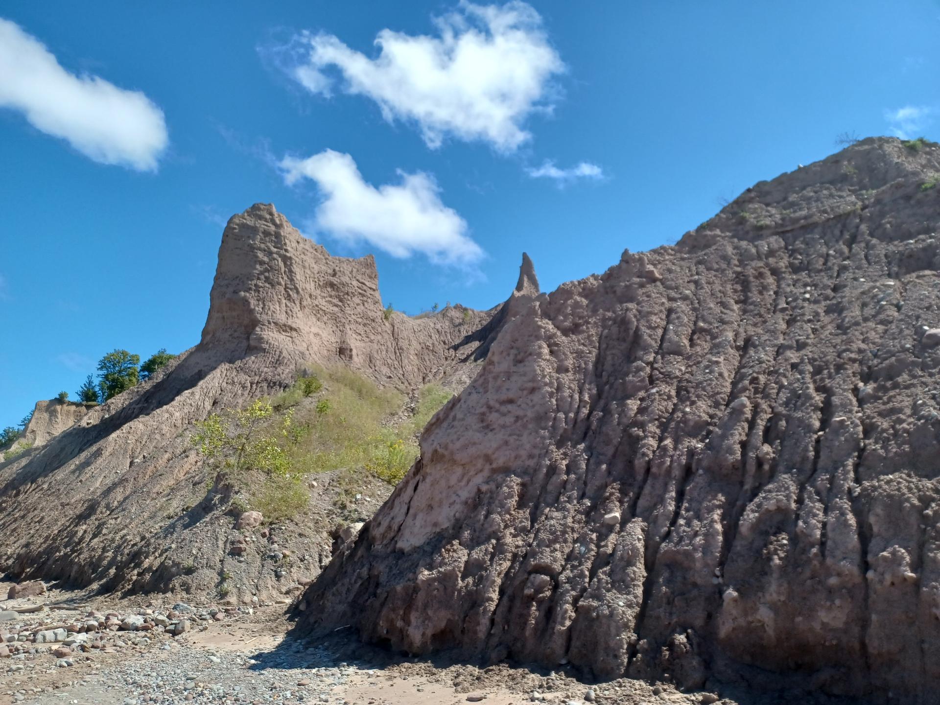 Towering, eroded rock formations under a bright blue sky with white clouds.