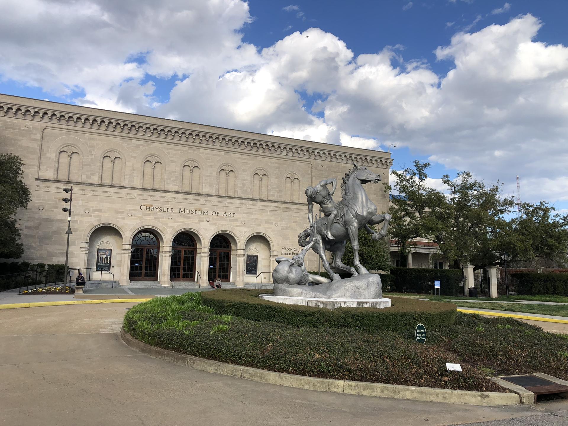 Stone building with a large equestrian sculpture and a partly cloudy sky.