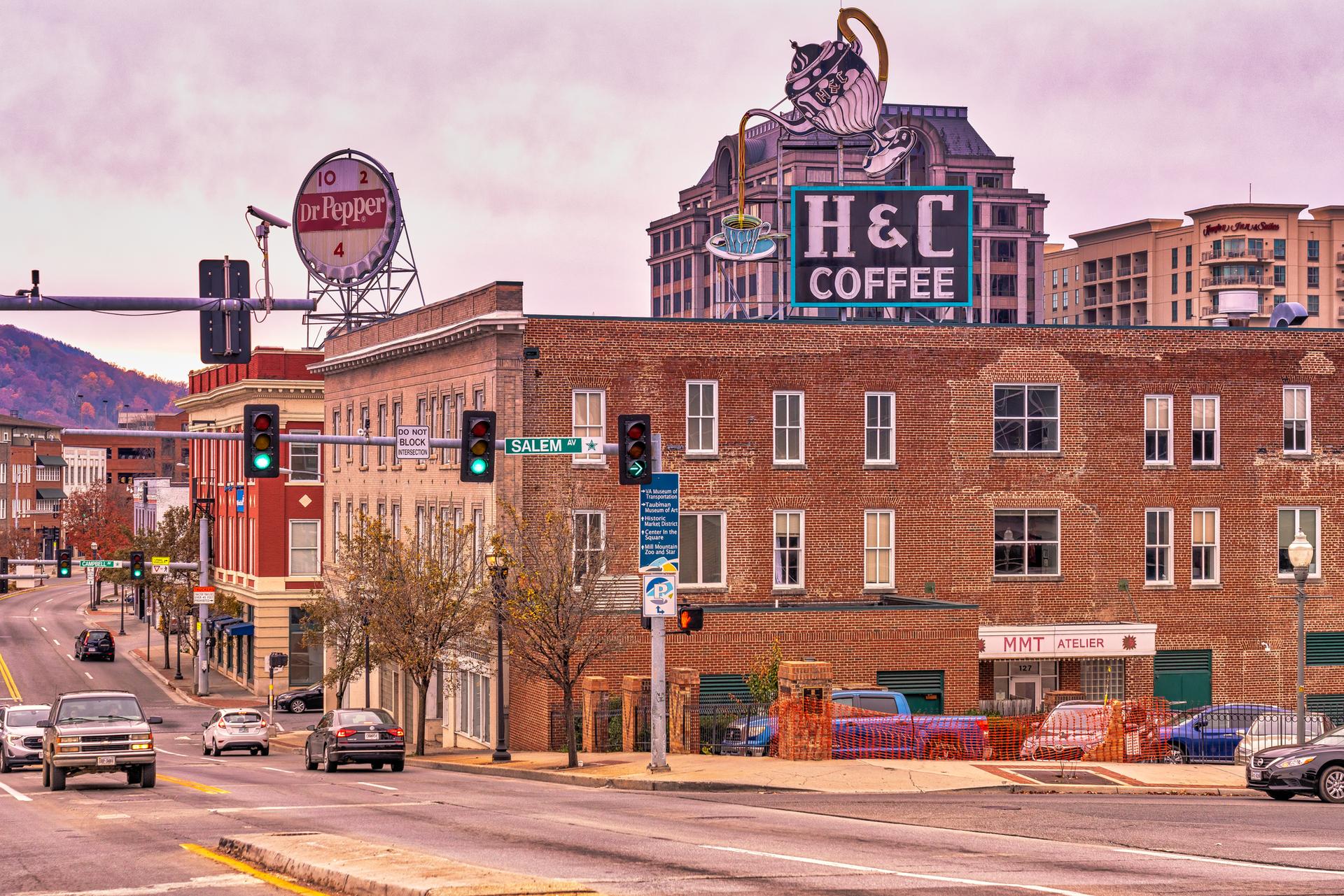 Busy city street with historic buildings, large signs, and cars.