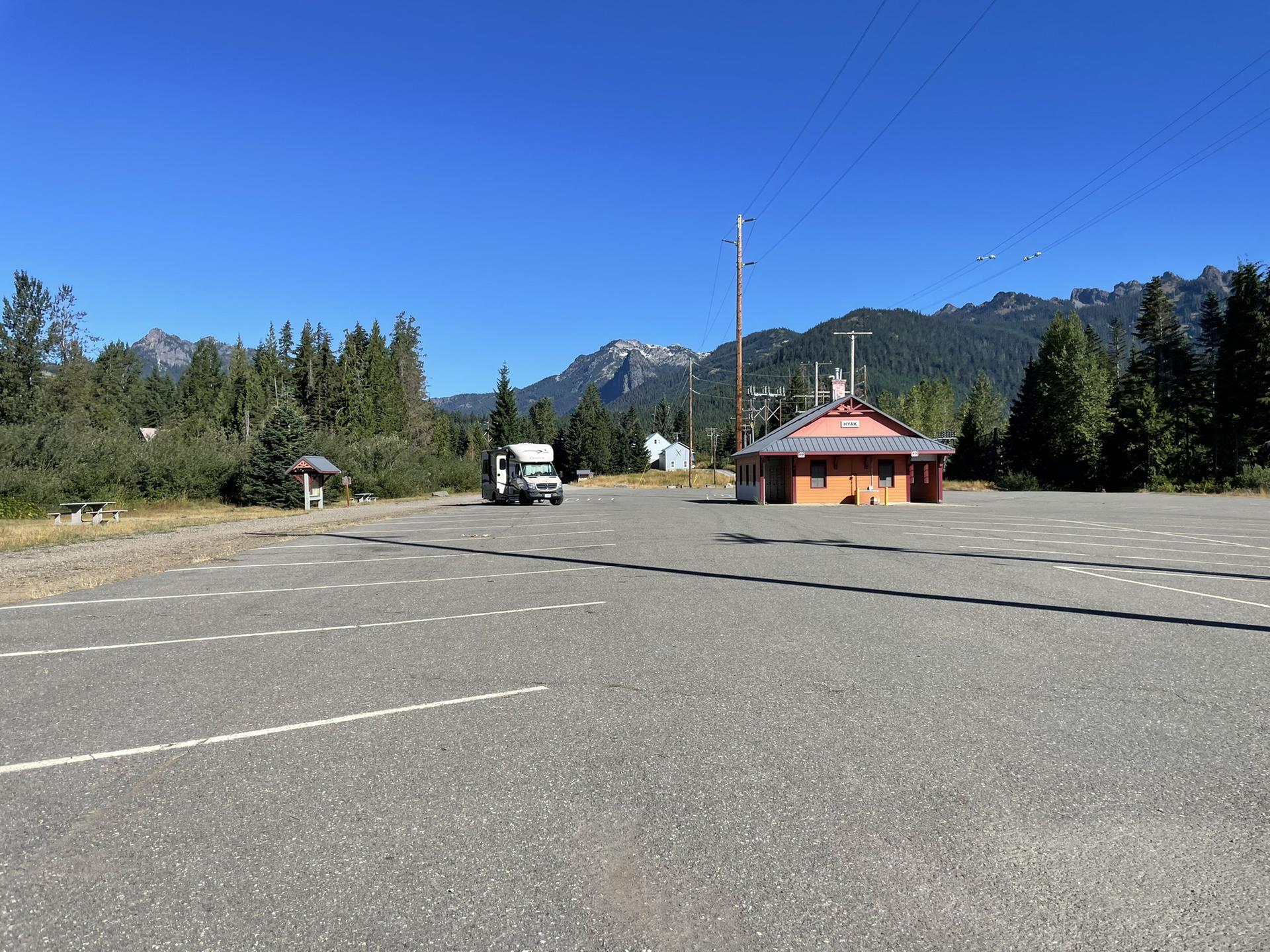 A large empty parking lot with mountains and a building under clear skies.