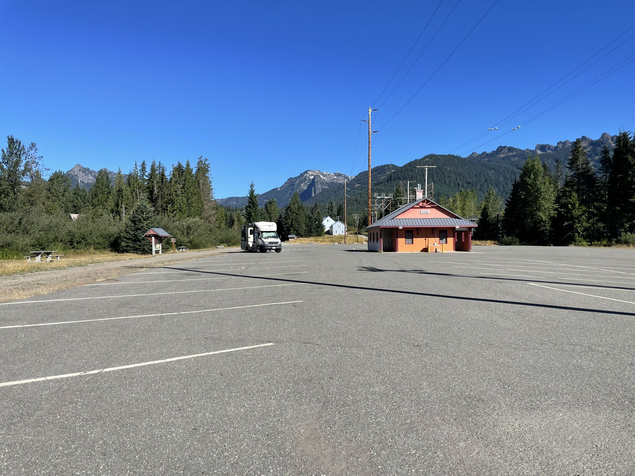 A large empty parking lot with mountains and a building under clear skies. - Mount Hyak loop via Forest Road loop