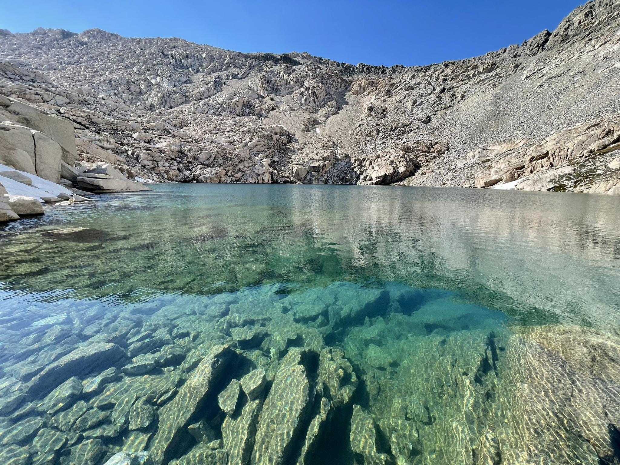 A clear, turquoise mountain lake surrounded by rocky, barren slopes.