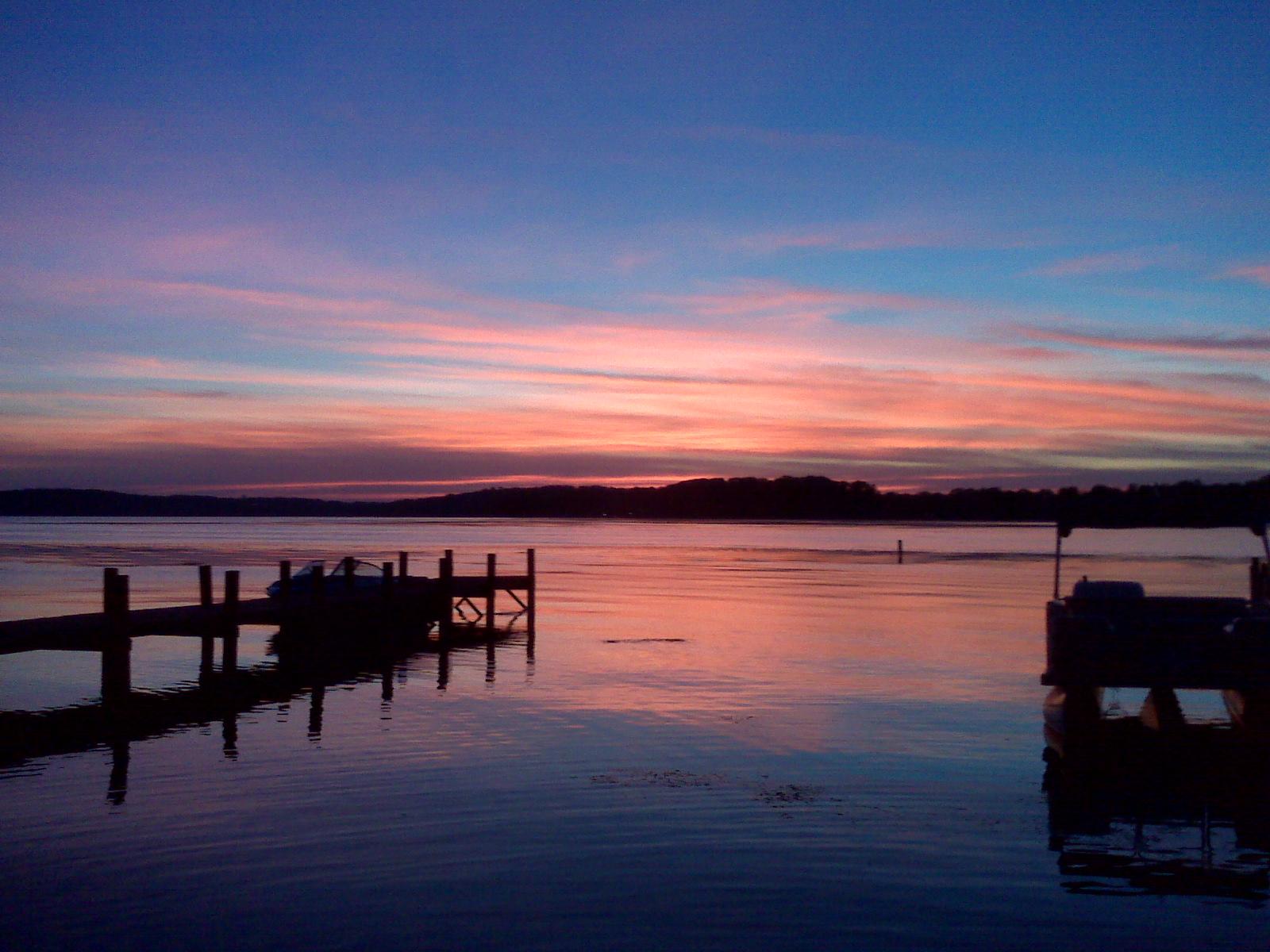 Serene lake with wooden docks at sunset, vibrant pink and blue sky.