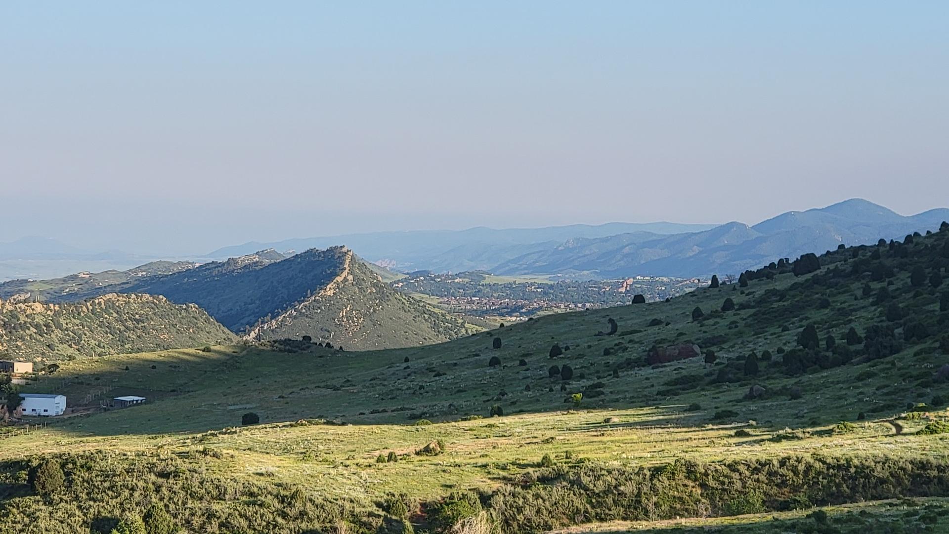 Green rolling hills and distant mountains under a clear morning sky.