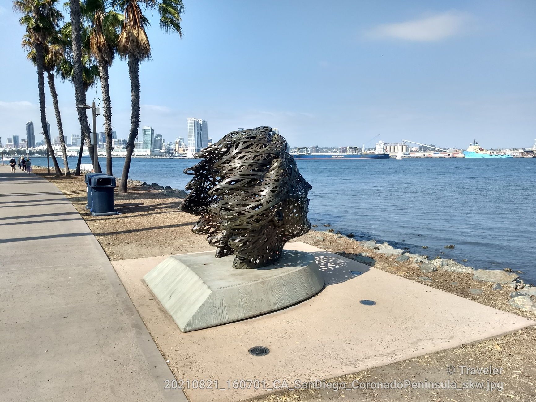 Abstract metal sculpture on a waterfront promenade with palm trees and city. - Bayshore Bikeway