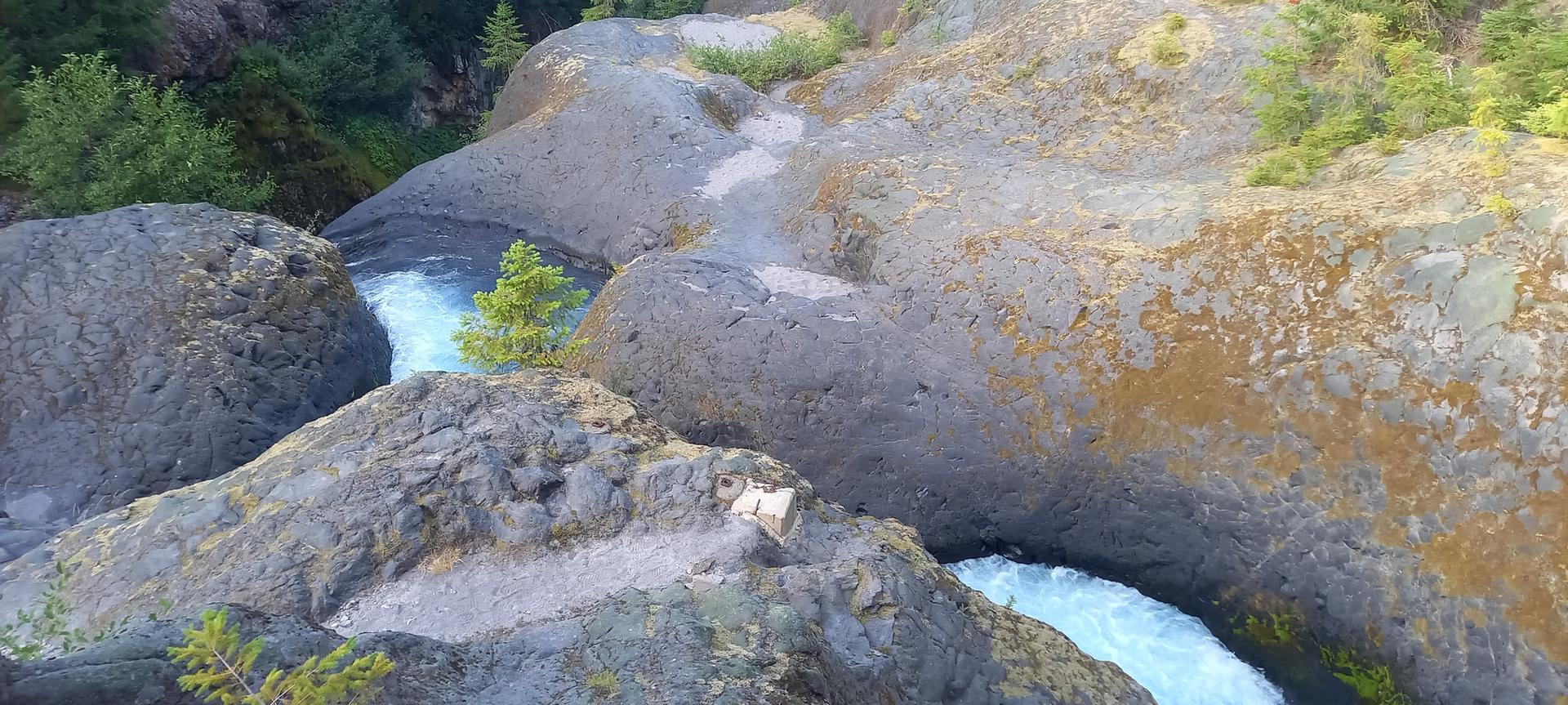 A river flows through a narrow, rocky canyon under bright daylight.