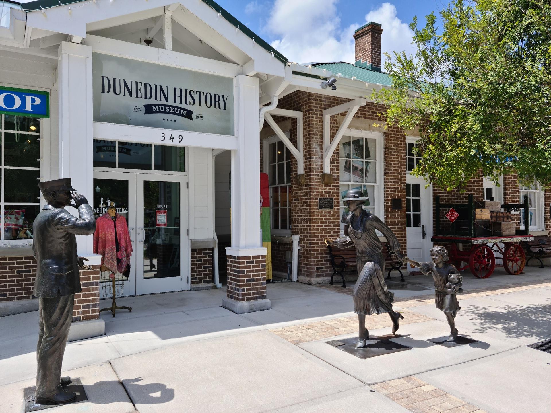 Sunny view of a museum building with three bronze statues outside.