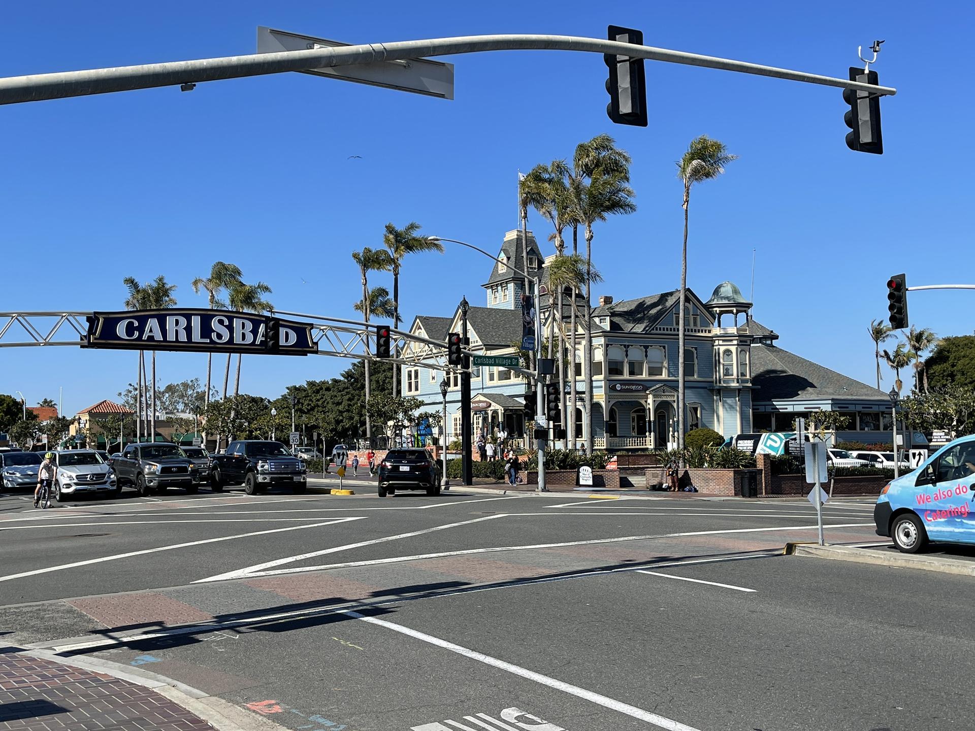 Busy city intersection with historic buildings, palm trees, cars, and clear sky.