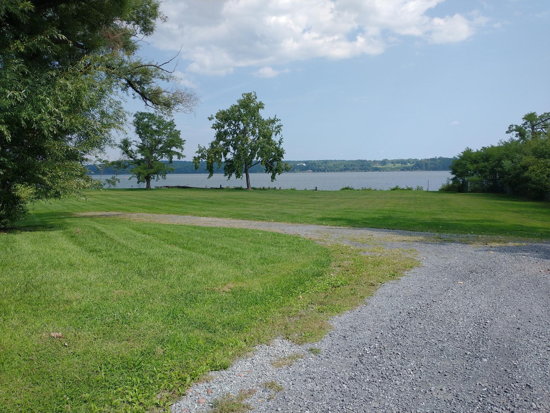 Grassy lawn and gravel path leading to a wide body of water.