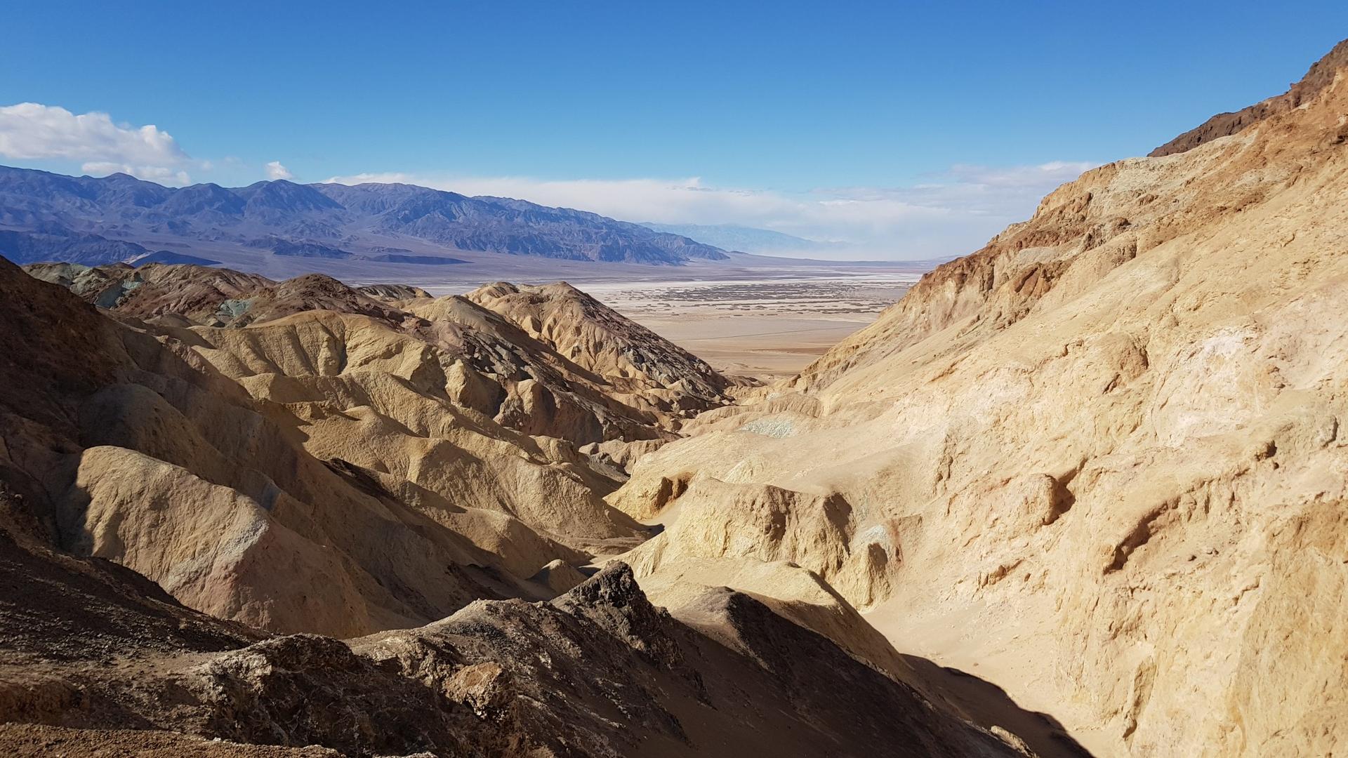 Expansive desert valley with rugged mountains under a clear blue sky.