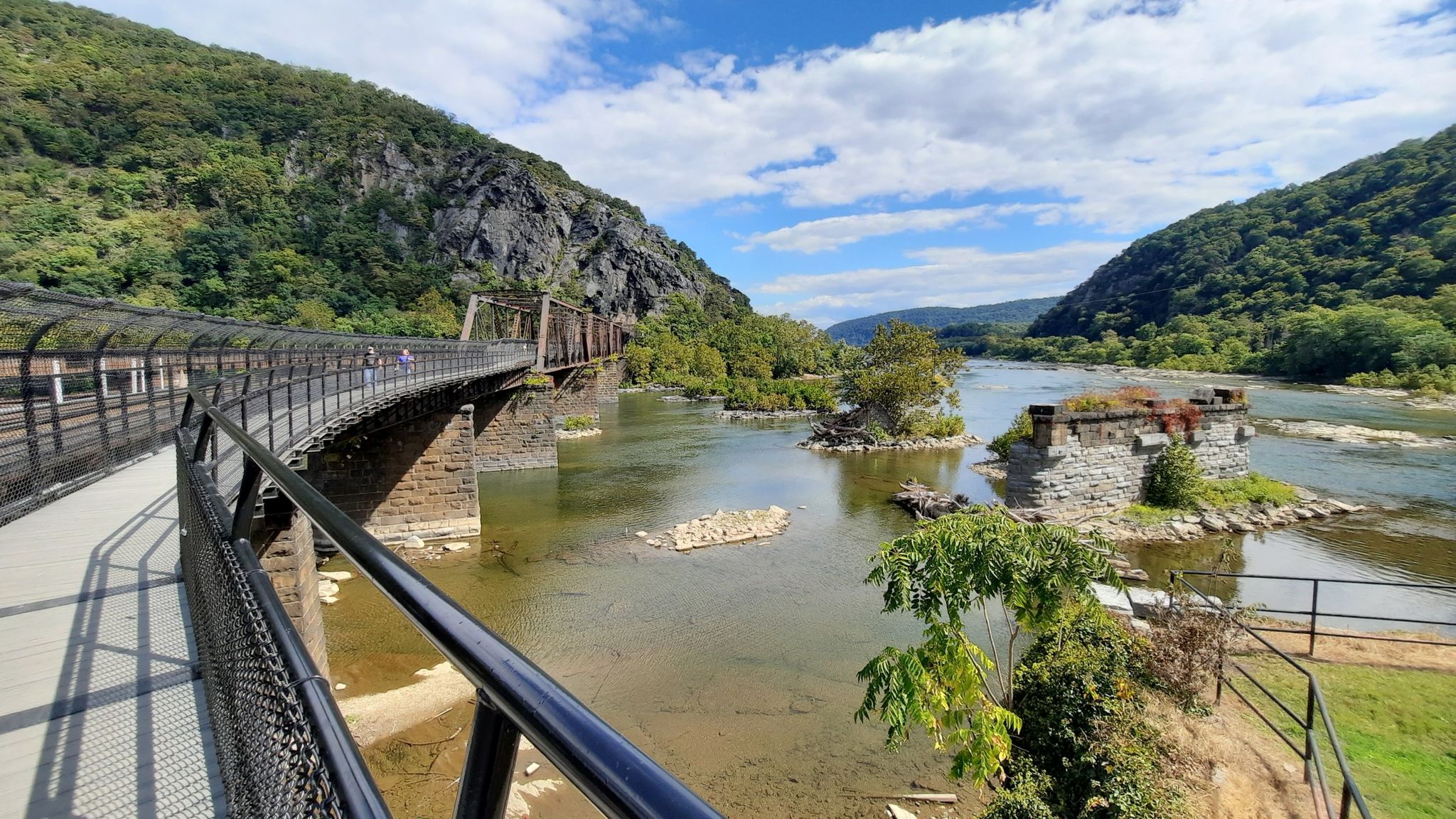 Bridge over river with stone ruins, green mountains, and blue sky. - Harpers Ferry Lower Town Trail Loop