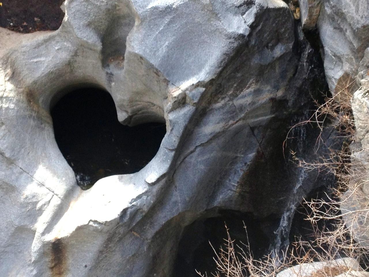 Heart-shaped rock formation with dark water in a rocky canyon.