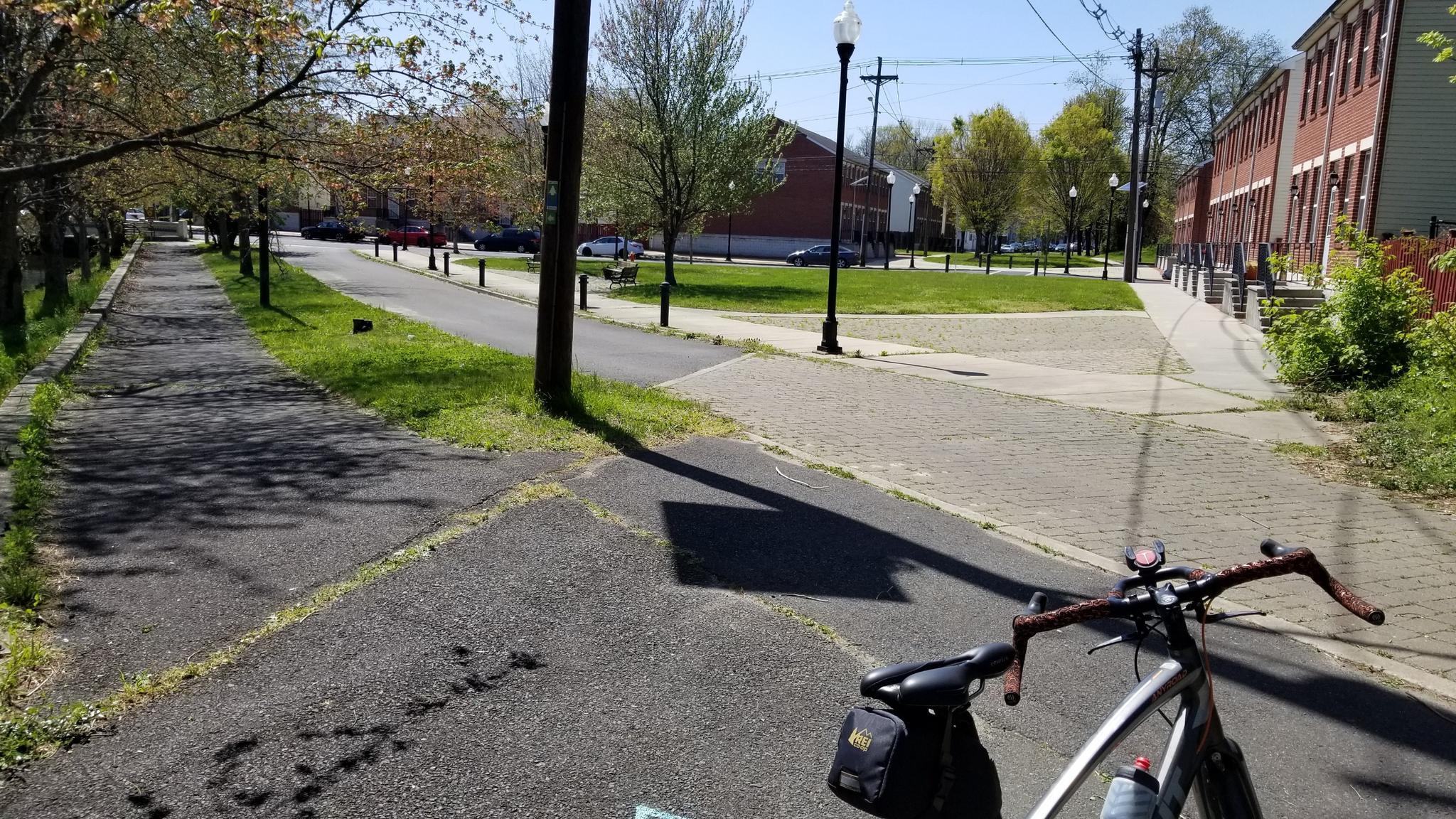 A bicycle rests on a paved path on a bright, sunny day.