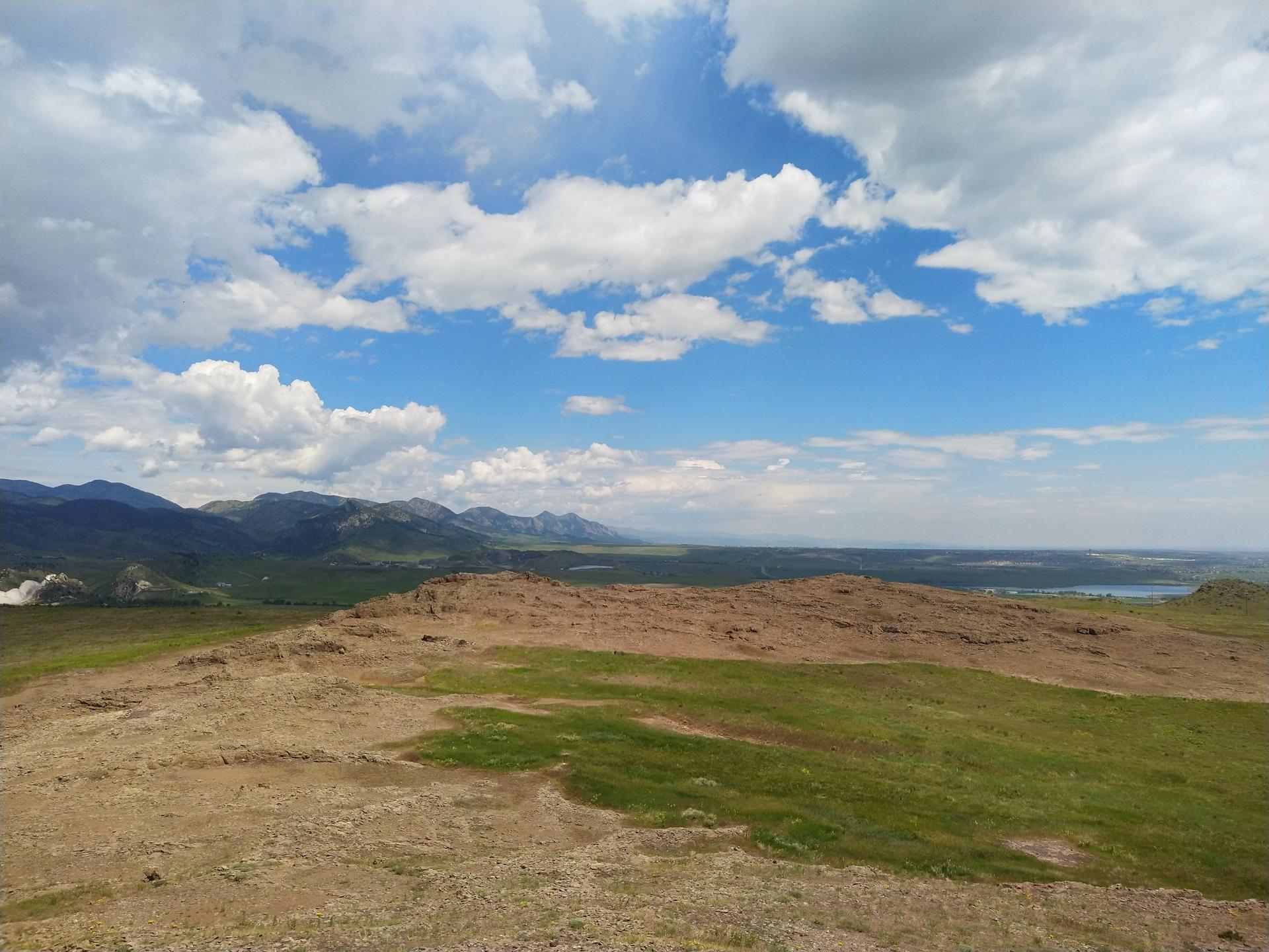Vast landscape with rolling hills, distant mountains, and a partly cloudy sky.
