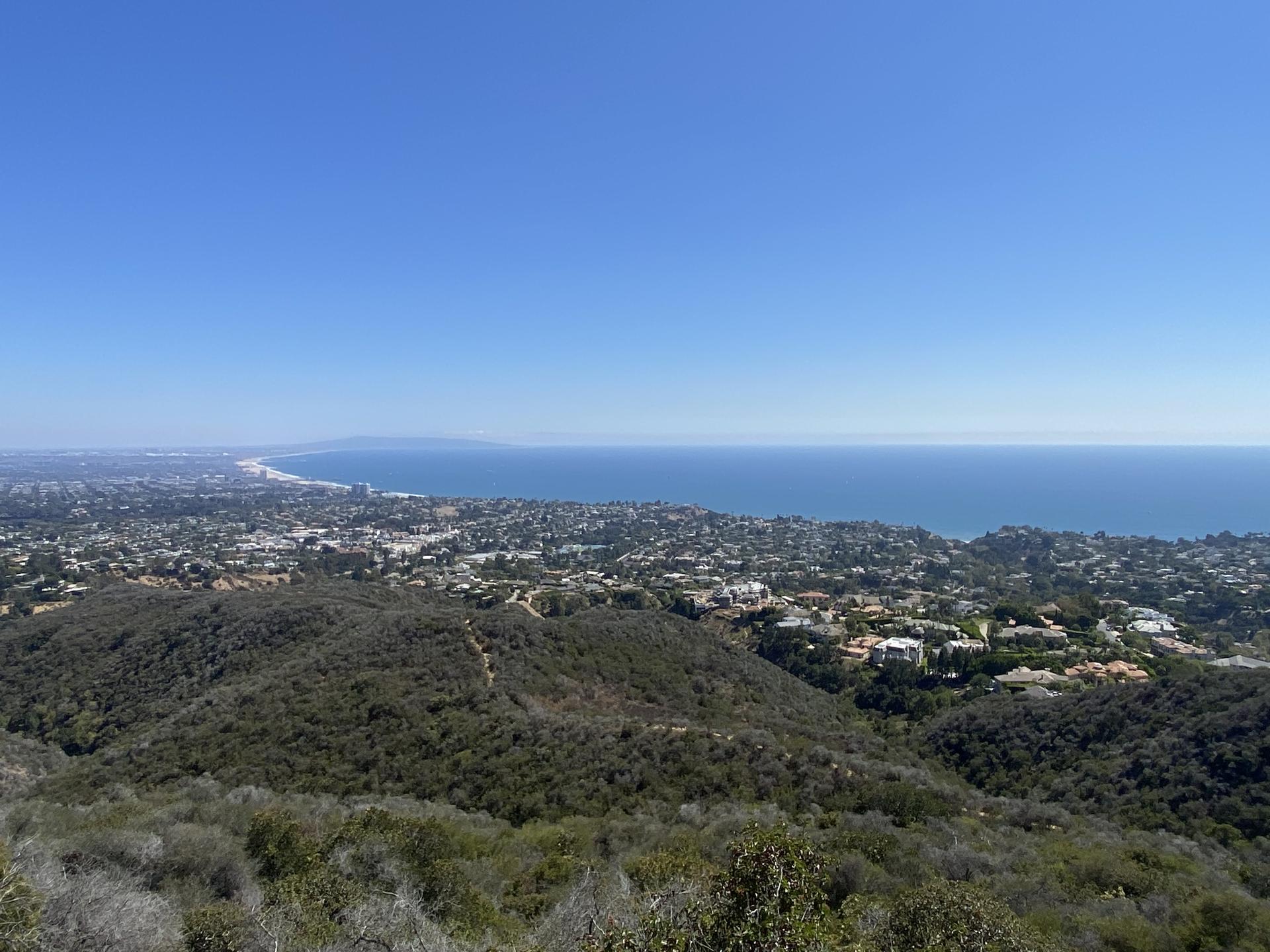 Panoramic view of a coastal city and ocean under a clear blue sky.