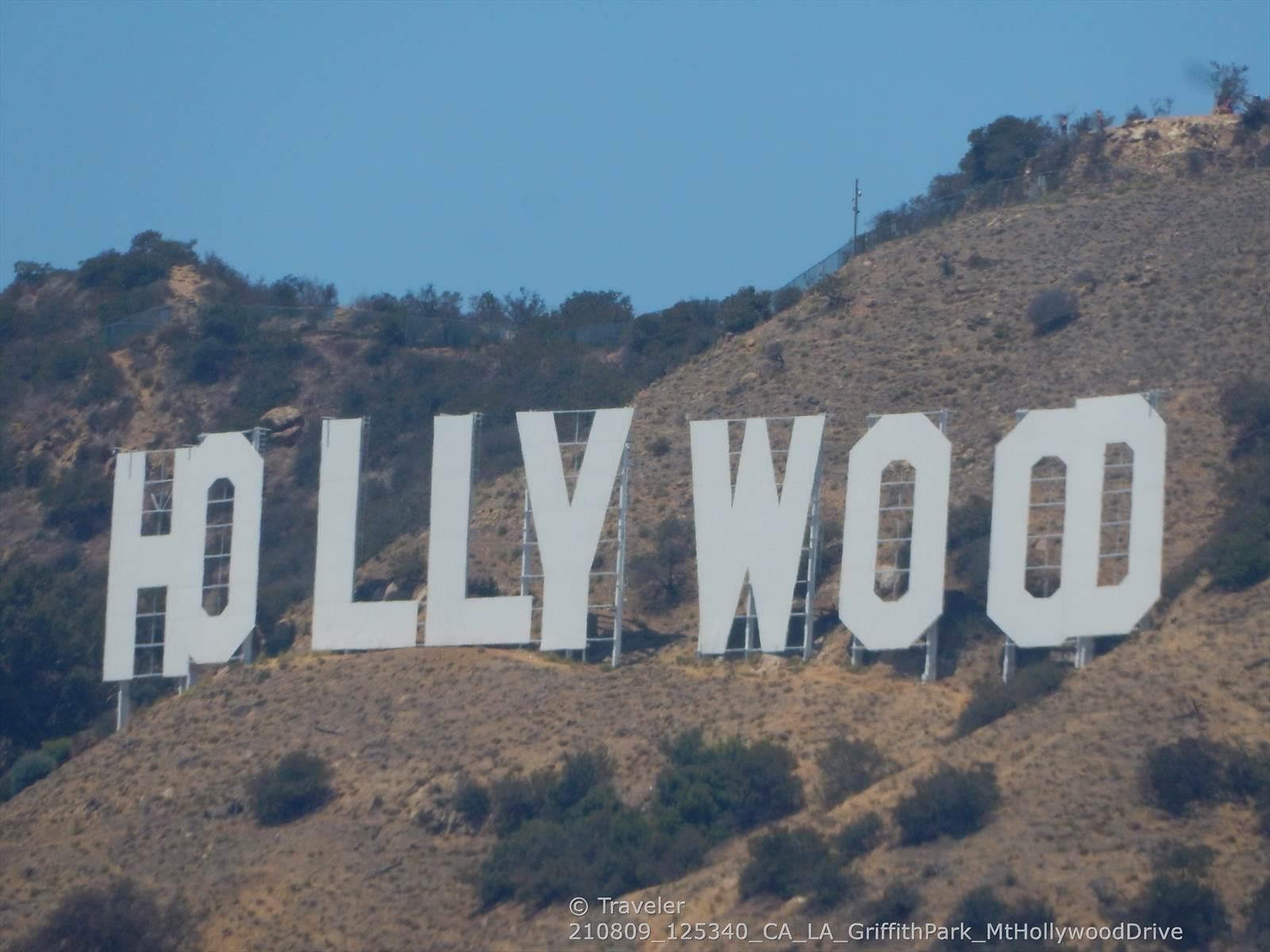 Large white letters on a dry, brush-covered hillside under a clear sky.