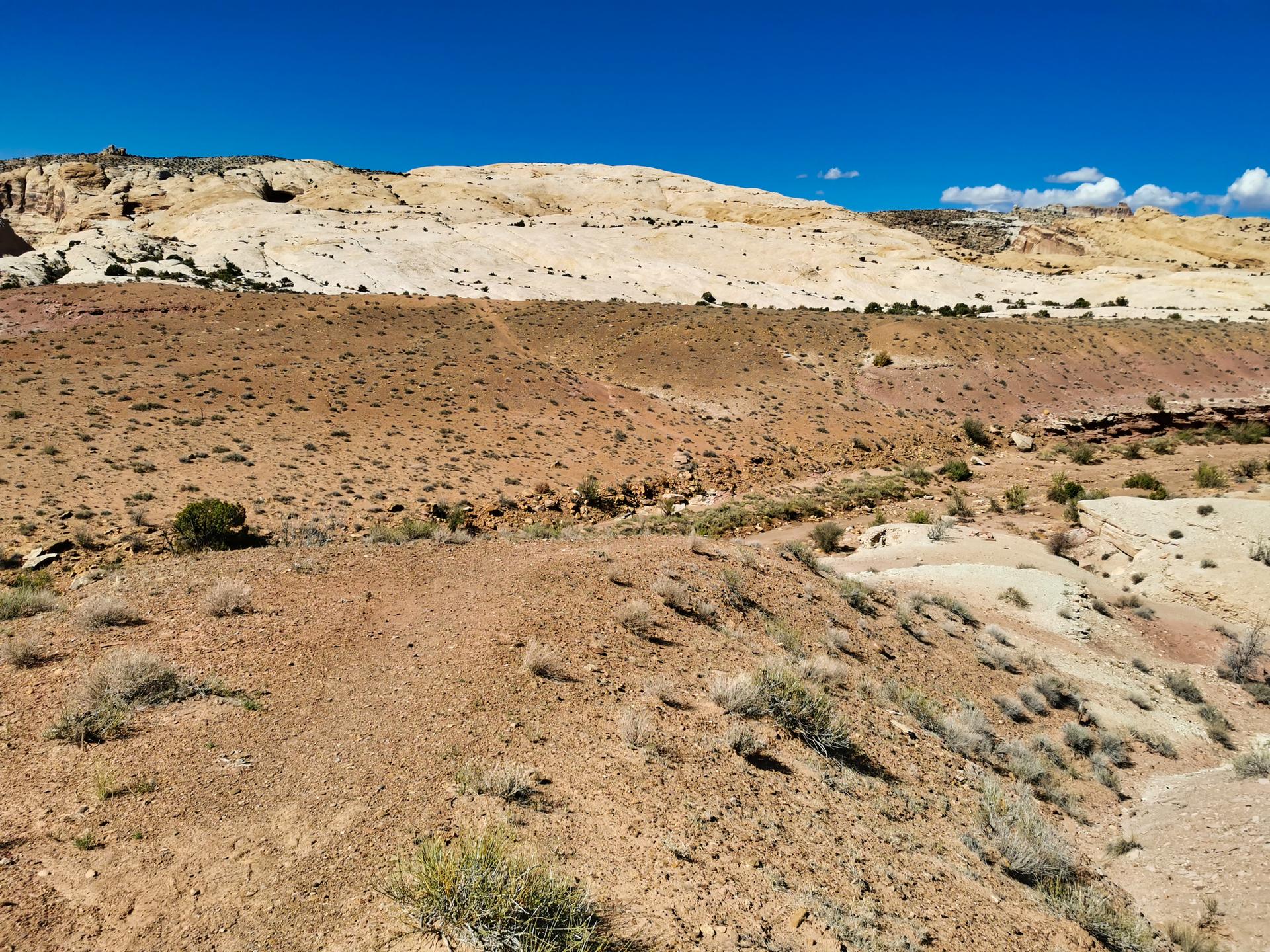 Expansive desert terrain with reddish-brown earth and light rock hills.