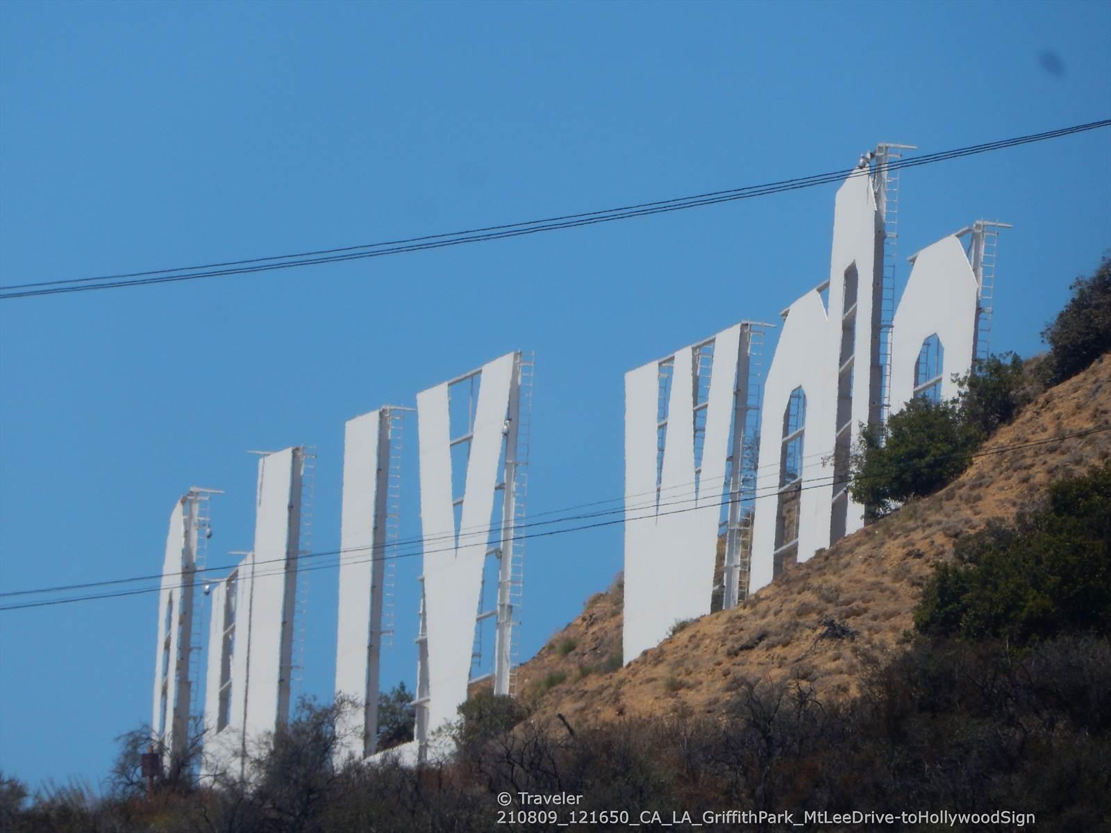 Close-up of large white letters on a dry, brush-covered hillside.