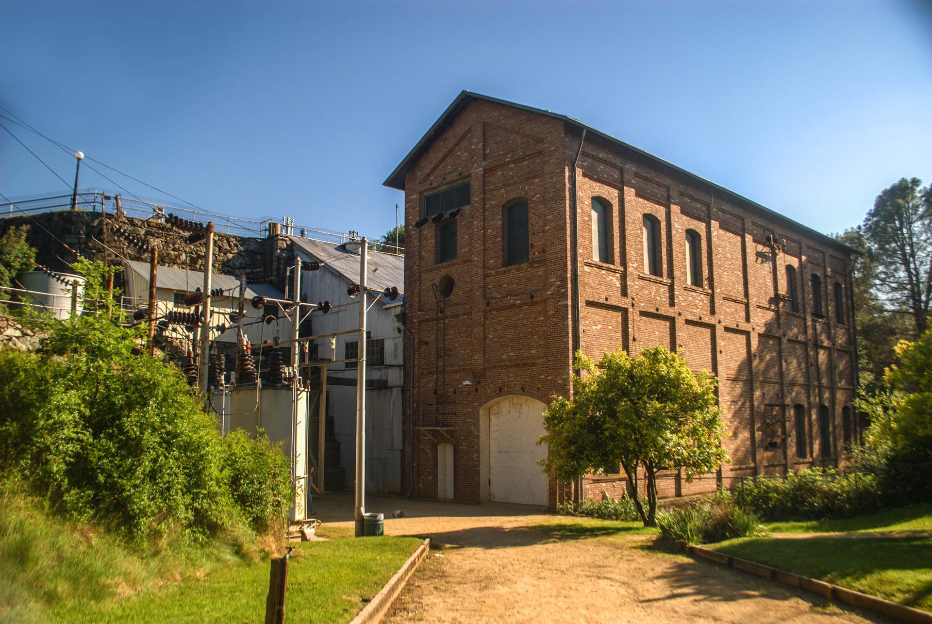 Historic brick building and industrial structures under a bright blue sky.