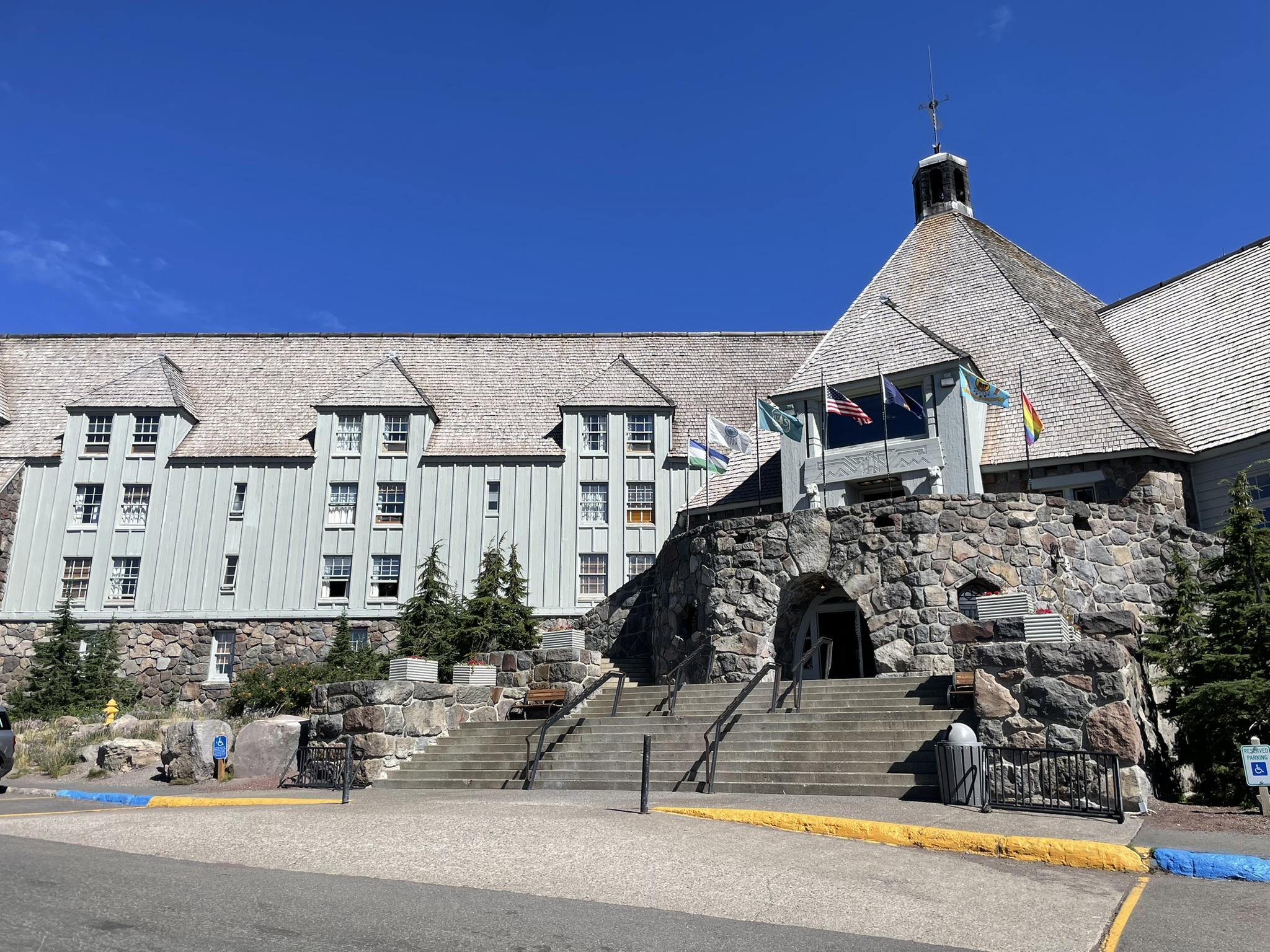 Grand stone and wood lodge with steps under a clear blue sky.