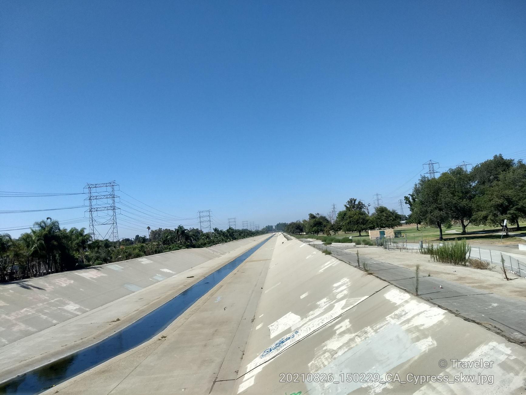 Long concrete channel with water under a clear blue sky.