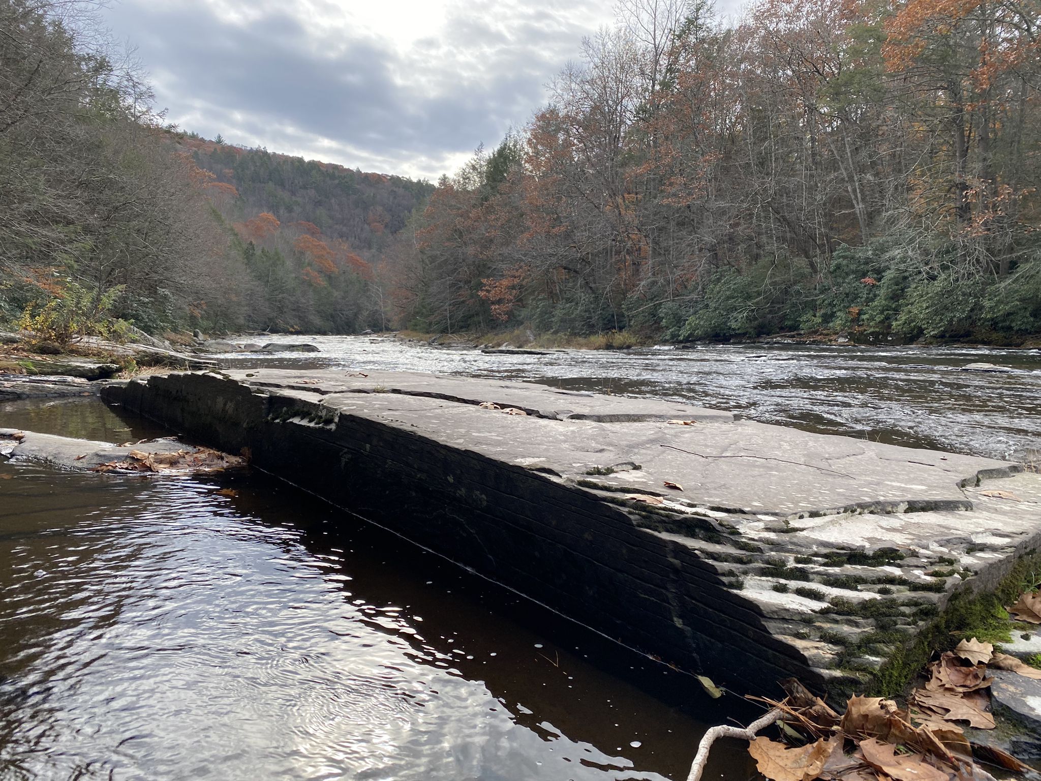 Wide river with large rock formations and forested hills under a cloudy sky. - Mullet Falls – Neversink River Waterfalls loop from Mullet Falls