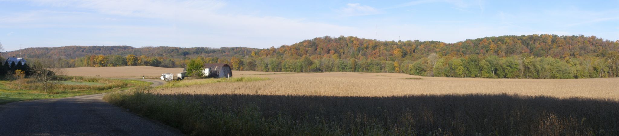 Panoramic view of harvested fields, small buildings, and distant wooded hills. - Goodenow Groove Nature Preserve & Plum Valley loop