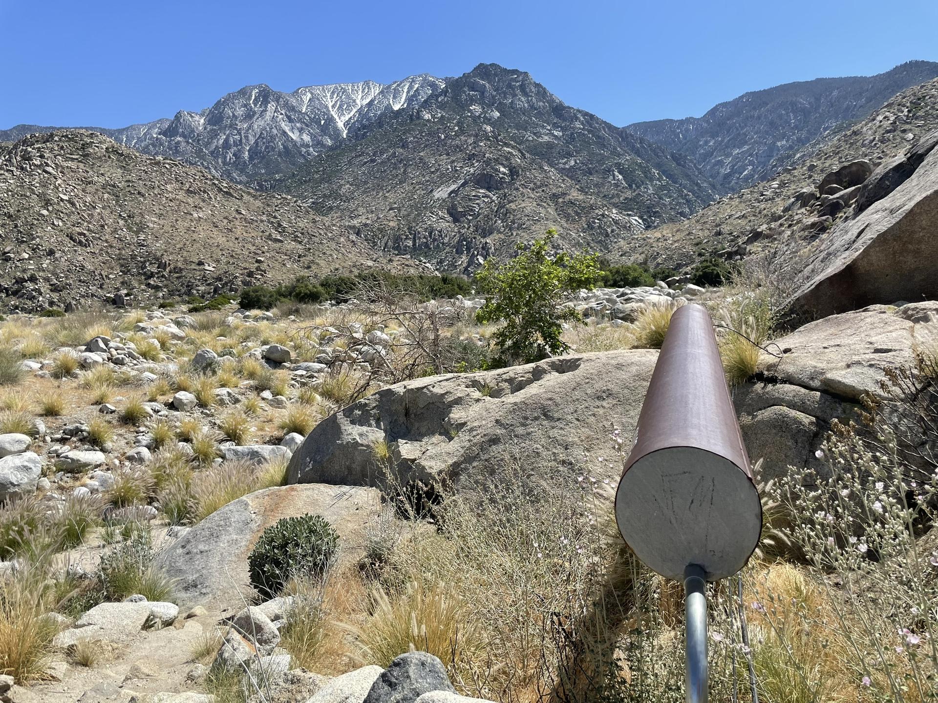 Large pipe in a rocky, dry landscape with snow-capped mountains in background.