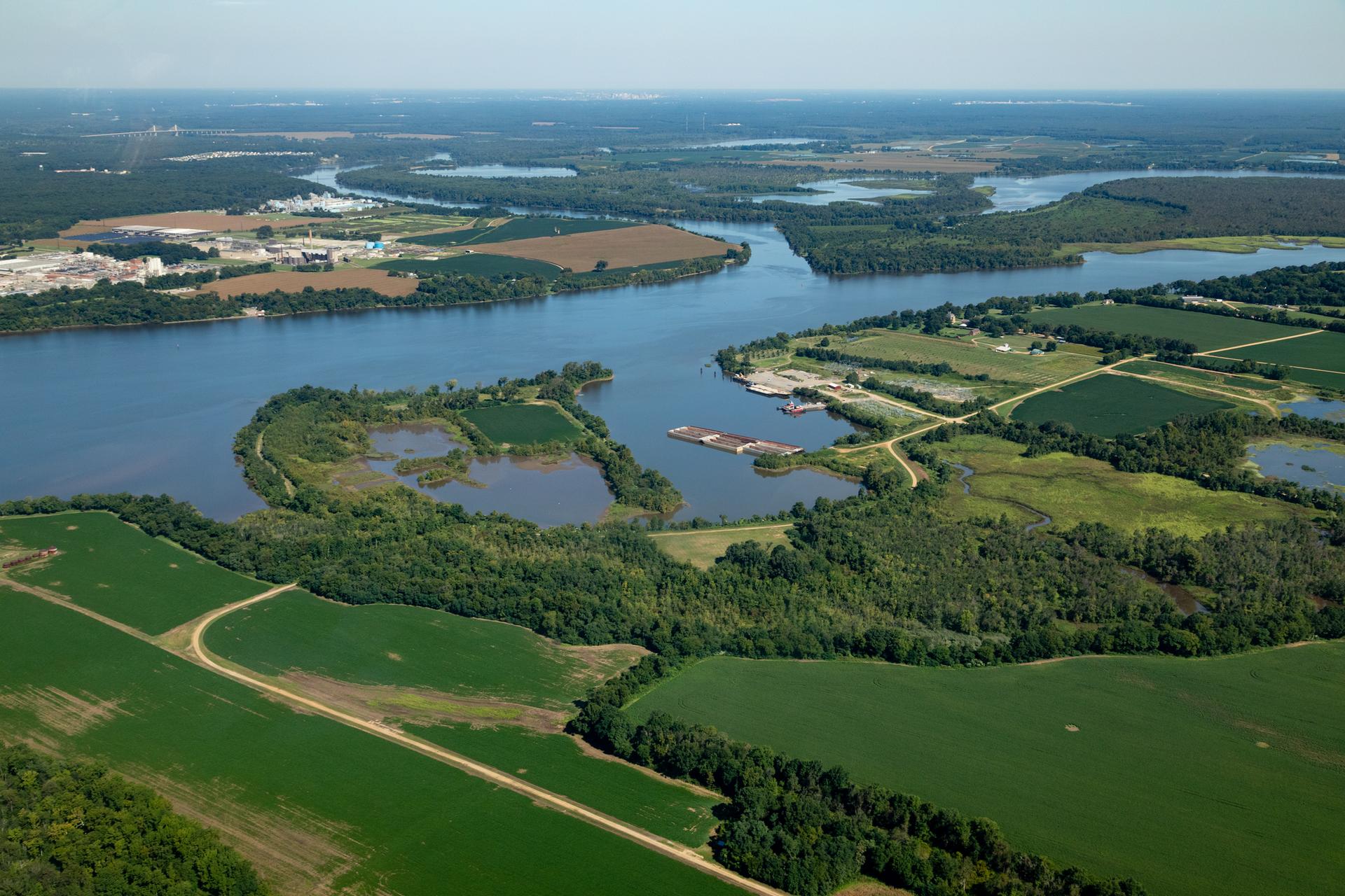 Aerial view of a wide river winding through green fields and forests.