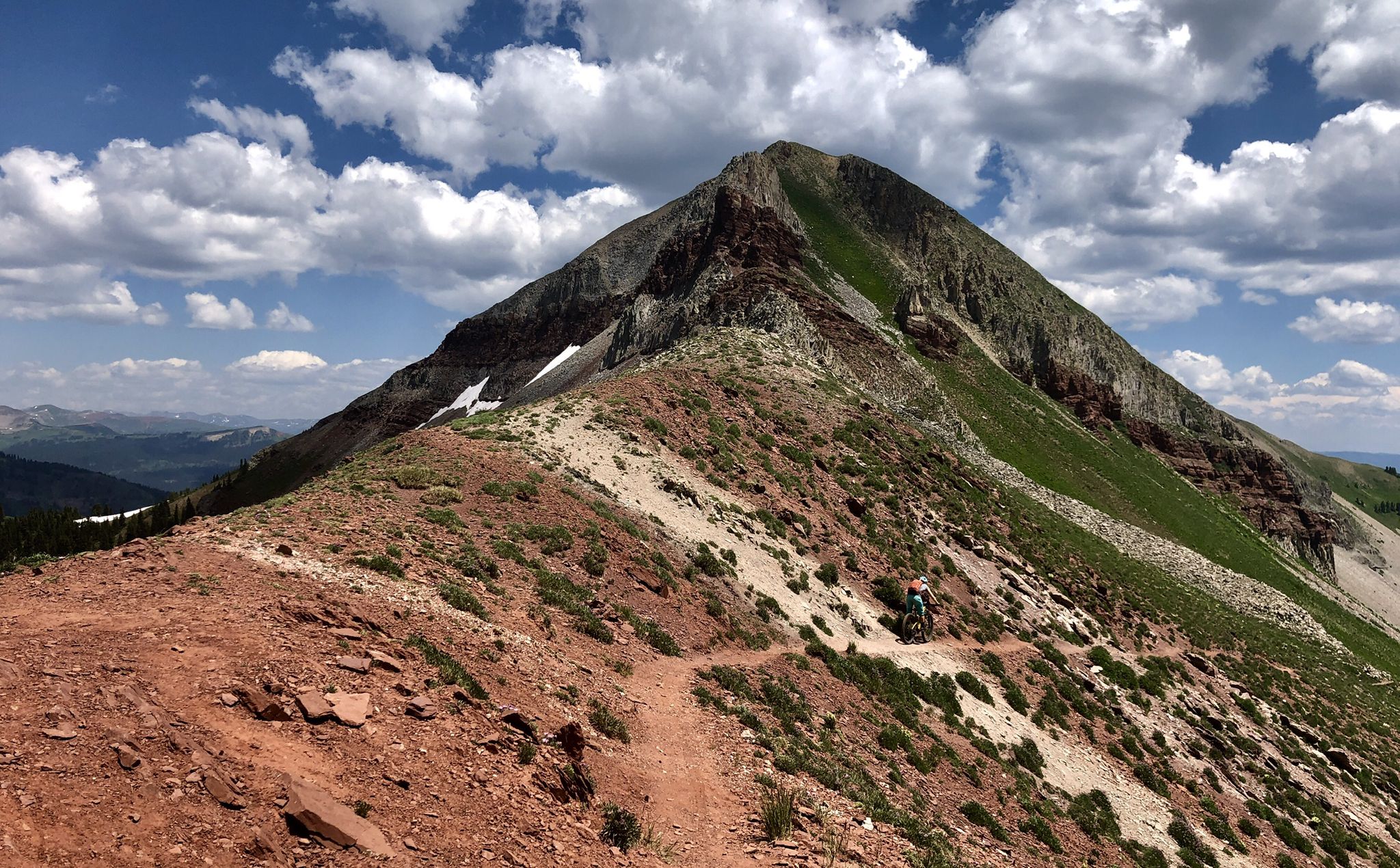 Mountain biker on a narrow trail ascending a rocky, green peak under a cloudy sky. - Black Hawk Pass via Colorado Trail & Hermosa Peak Road loop gravel