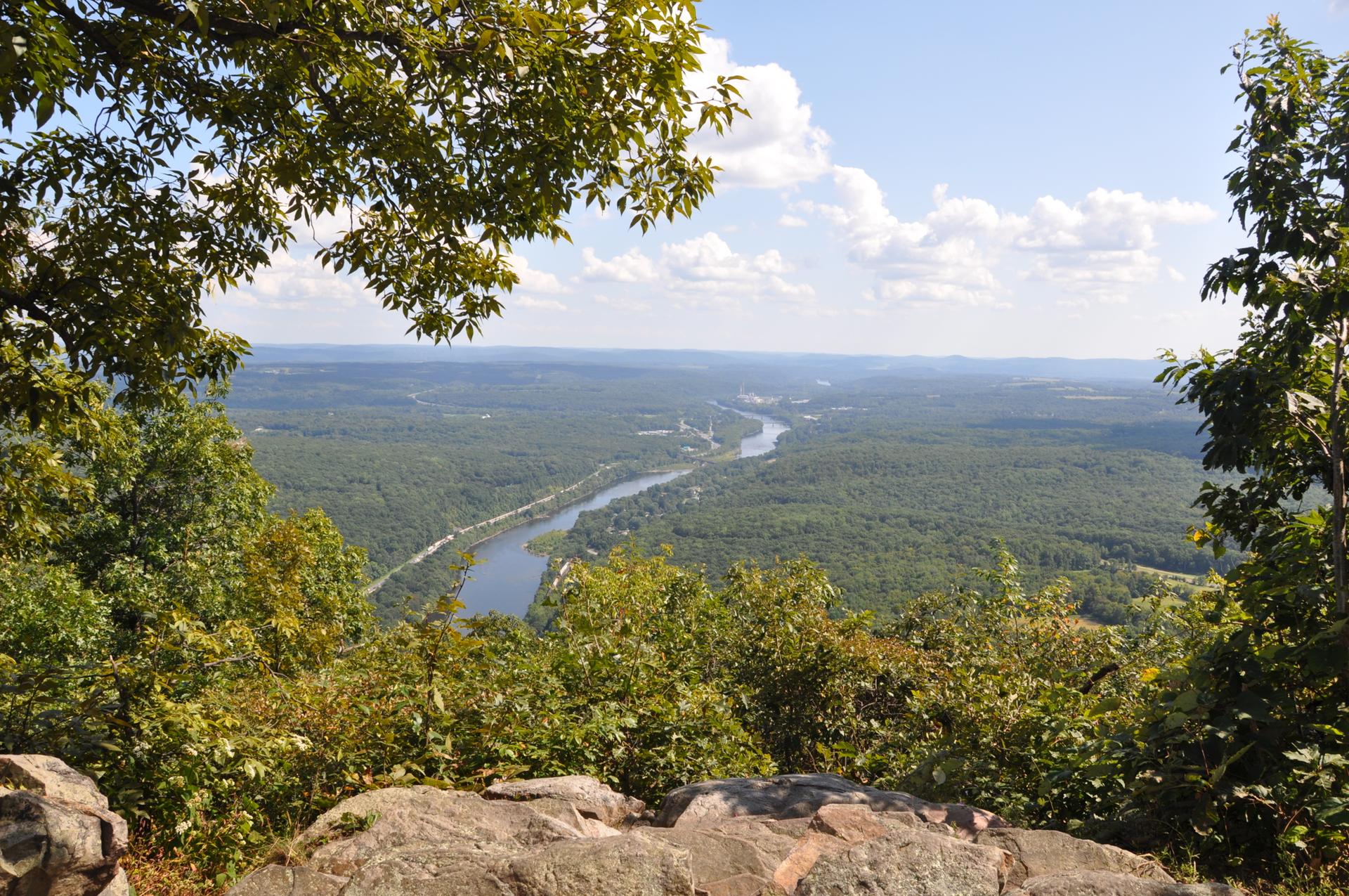Expansive view of a green river valley from a rocky overlook.