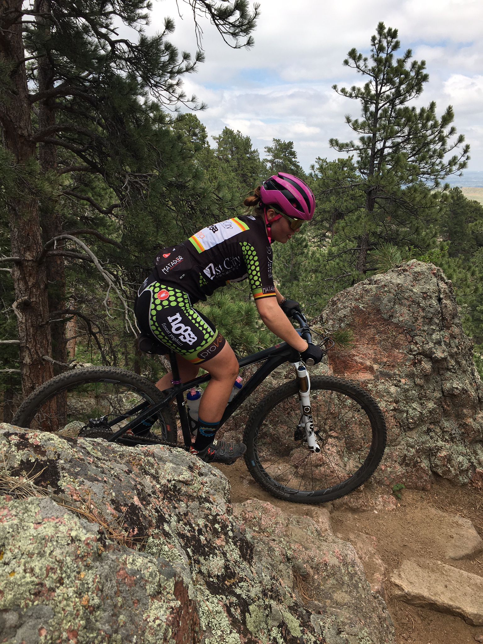 Woman mountain biking over rocky terrain on a forested trail under bright skies. - Swan Johnson, Sawmill and Shoreline Trail Loop