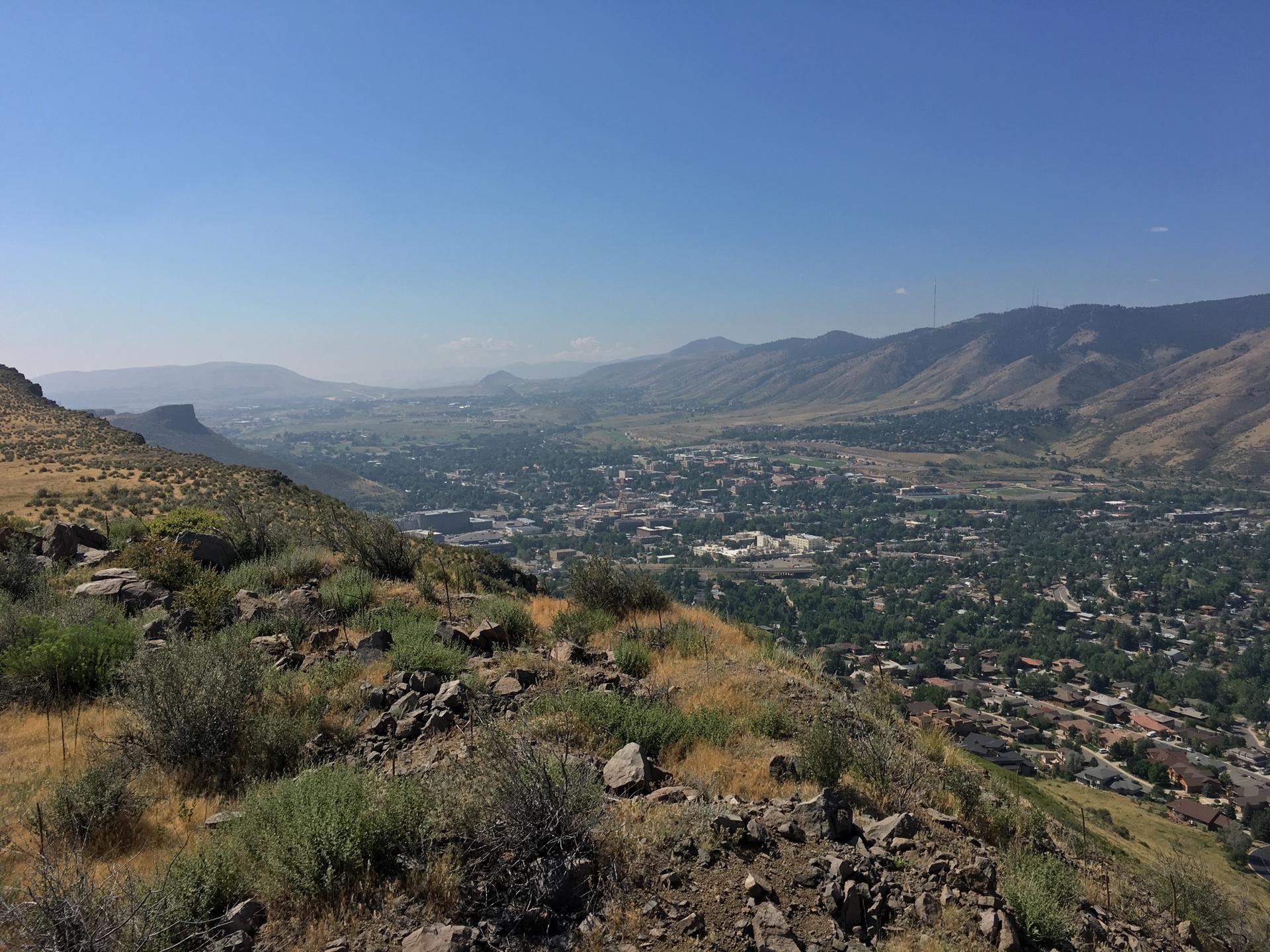 Sunny mountain overlook of a sprawling city in a valley with clear skies.