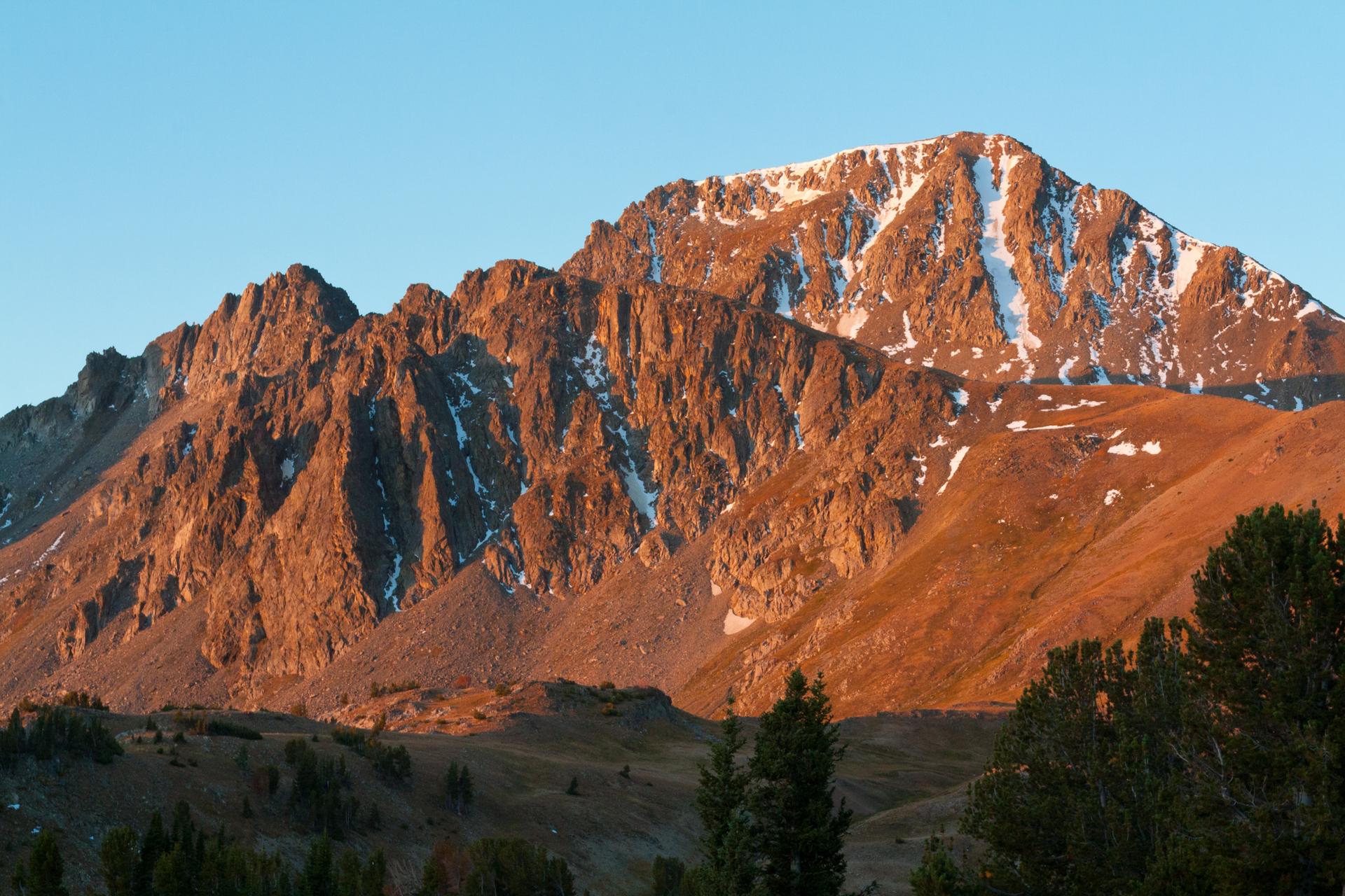 A rugged, snow-capped mountain bathed in warm golden light.