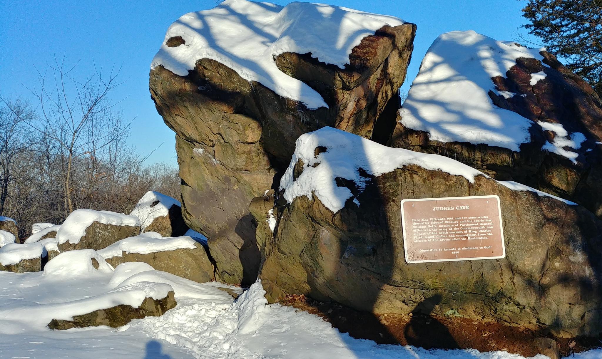 Large snow-covered rocks with a plaque on a sunny winter day.