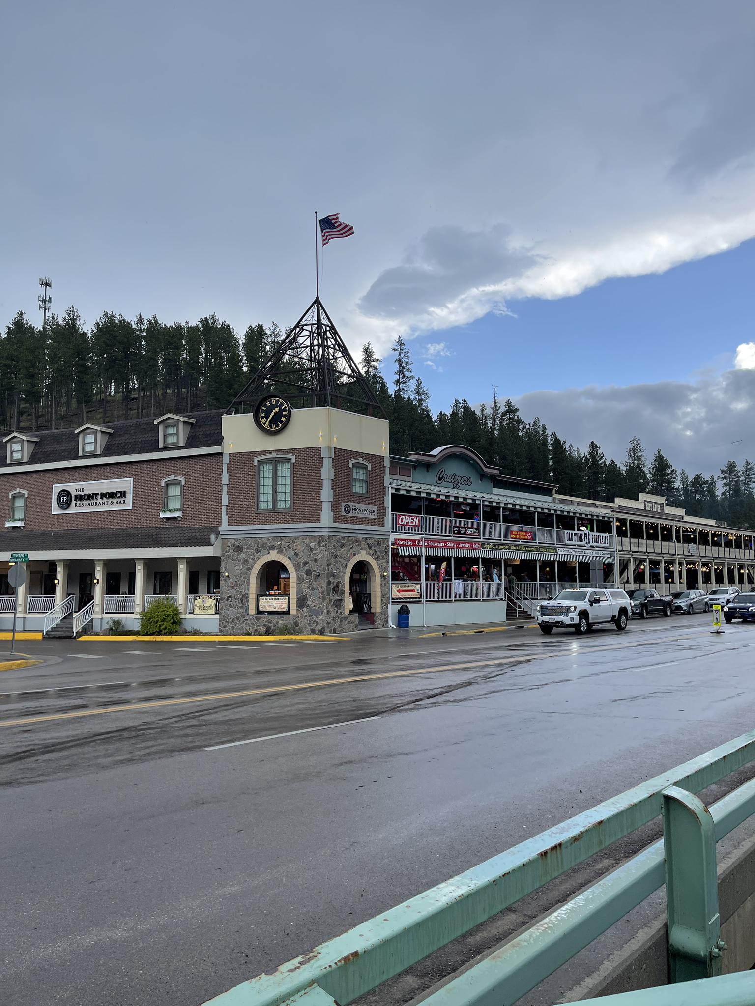 Street with cars in front of multi-story buildings under a cloudy sky.