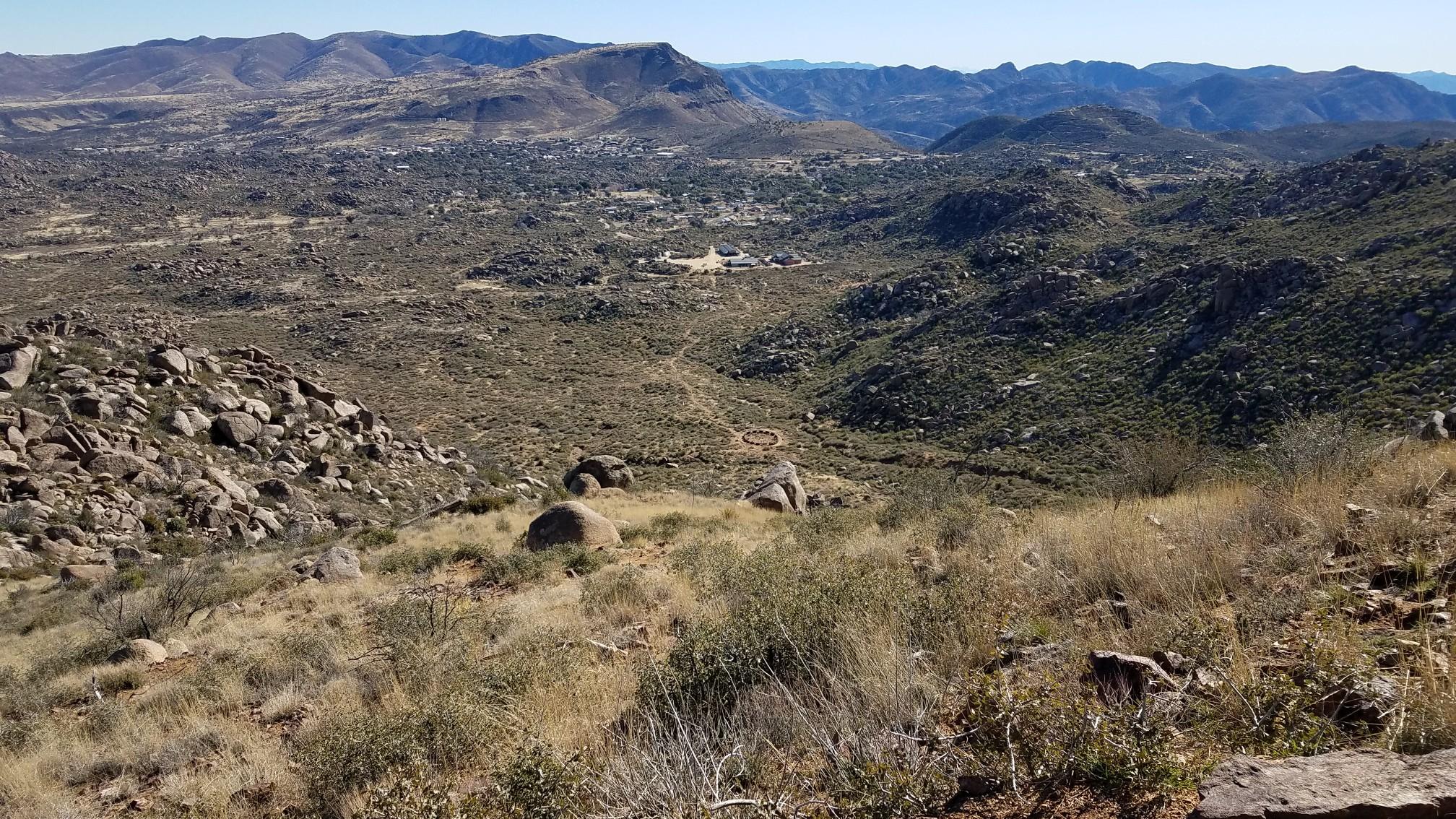Wide view of a rocky, arid valley and distant mountains under clear skies.
