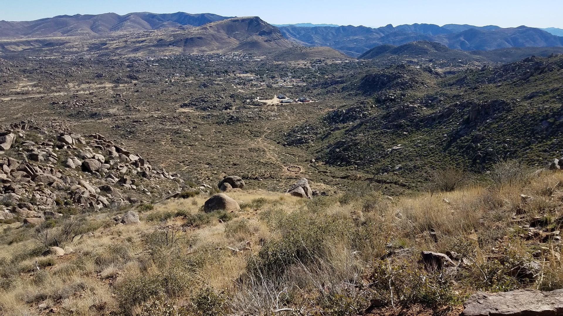 Wide view of a rocky, arid valley and distant mountains under clear skies.