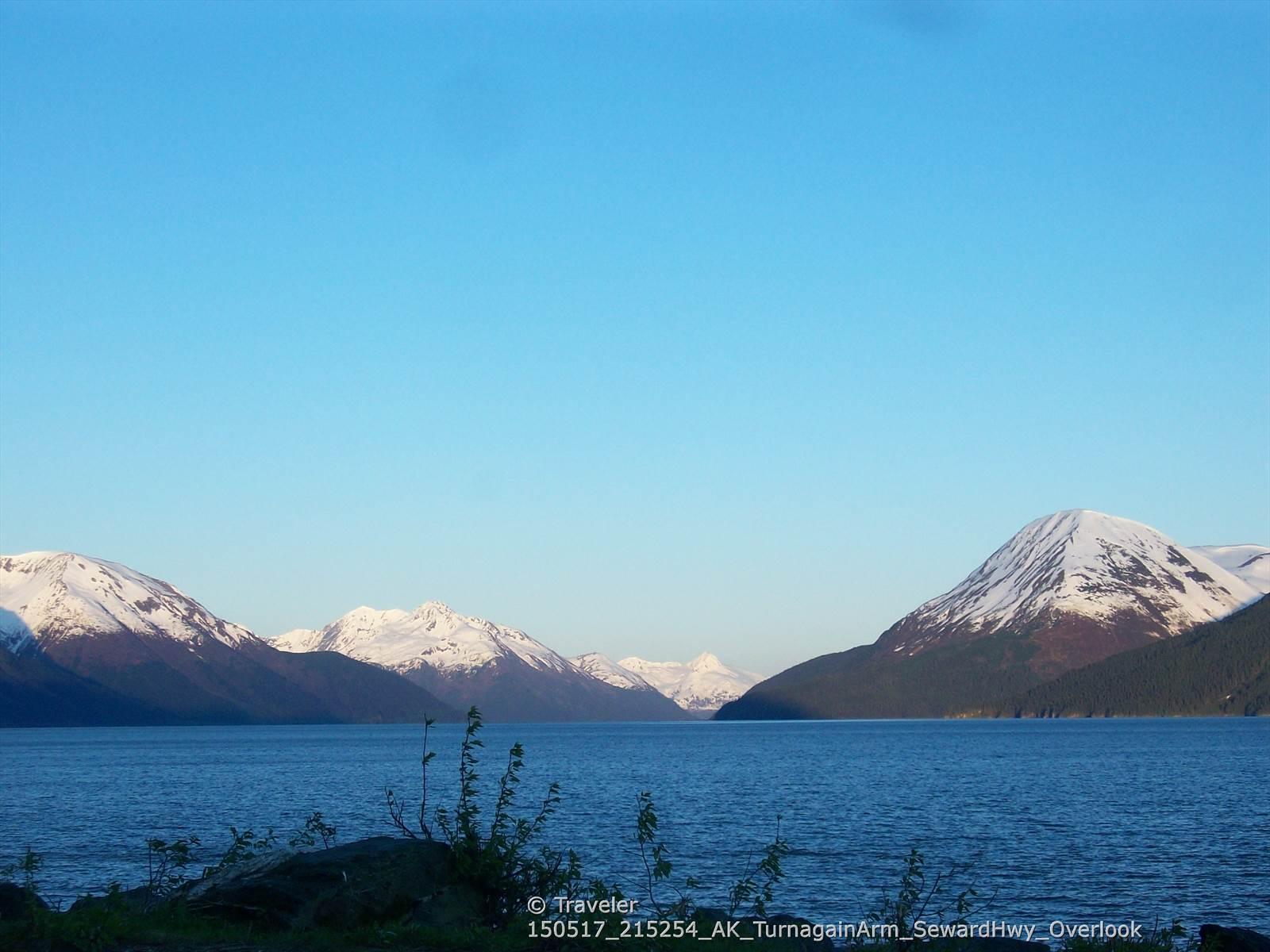 Clear blue water and snow-capped mountains under a bright sky.
