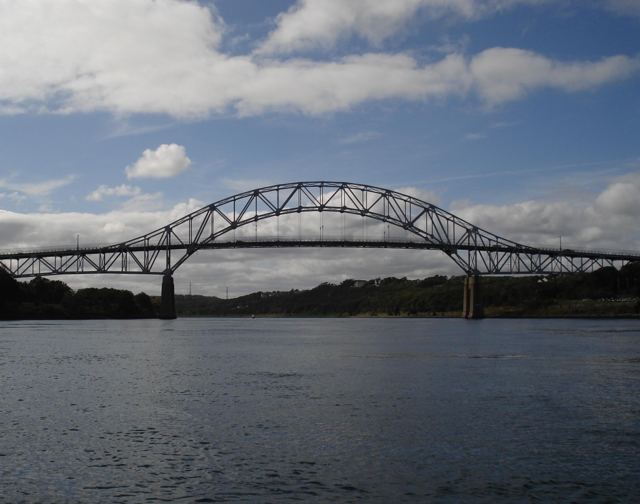A large steel arched bridge spans a wide body of water.